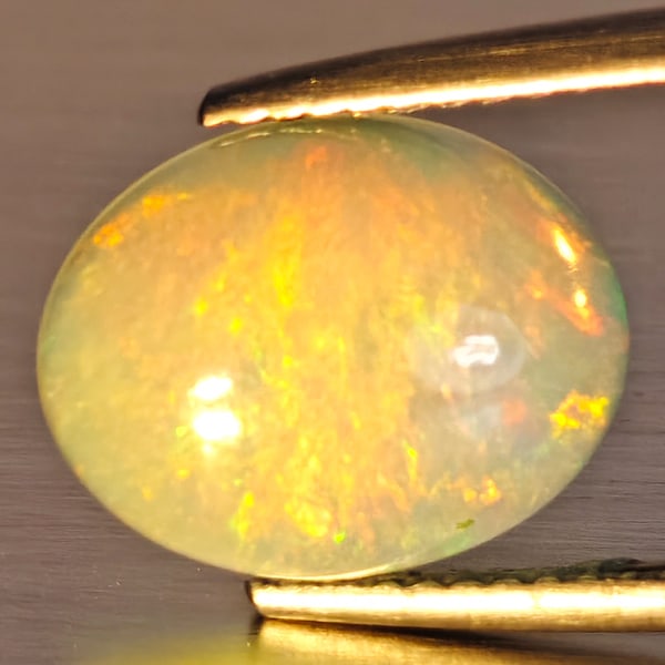 Natural Multi-Color Play Of Colour Opal Gemstone 2.45 Ct. Oval Cabochon Shape 12.2 x 9.7 Mm.: Product ID: 708700145 Product Name: Natural Opal Weight: 2.45 CT. Size: 12.2 x 9.7 x 4.7 MM. Shape: Oval Cabochon Color: Multi-Color Clarity:Opaque Luster: Good Gems Origin: Ethiopia Treatment: Unheat