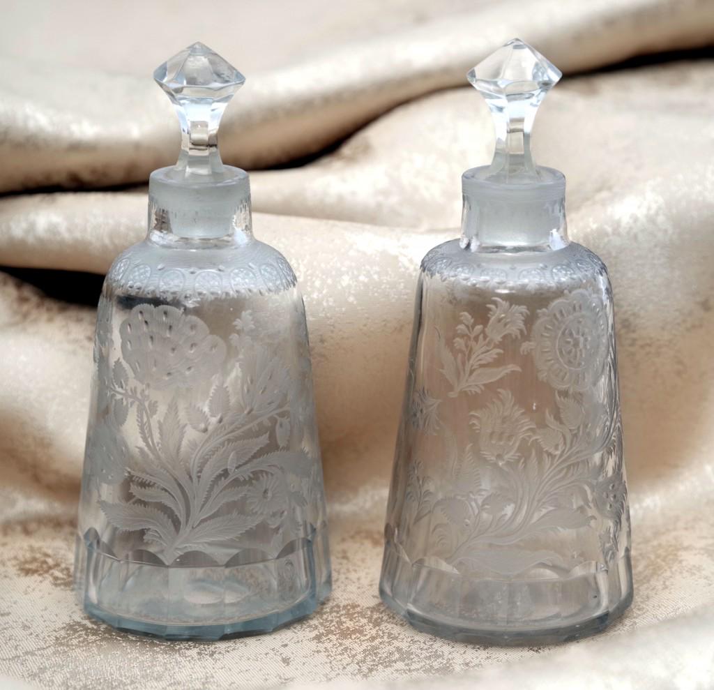 A pair of Flacons with Stoppers: Greyish glass. Flacons standing on polygonal bases. Conical shape, engraved with floral decoration. A lambrequin decorations at the top of the vessels. North Bohemian, 18th century, height 13 cm. Stop