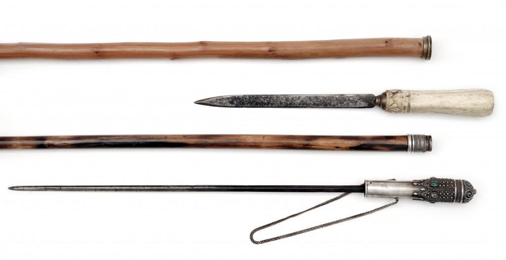 Two Walking Sticks: A sword cane with dagger. Straight diamond shaped blade, length 34.5 cm. The grip made of silver tone metal, set set with stone cabochons and decorated with filigree wire. Shaft of the stick from hard