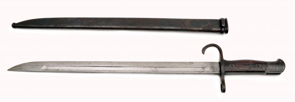 A Type 30 Bayonet for the Arisaka Rifle by Kokura: The straight single-edged blade with fullers on both sides. The Kokura Arsenal stacked cannonballs symbol on the ricasso. Rounded wooden grip and with a hooked quillon. Steel scabbard. Japan, Tokyo, 1