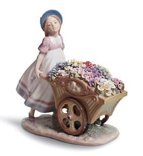 LLADRO "LOVE'S TENDER TOKEN" #6521: LLADRO "LOVES TENDER TOKEN" #6521, A LLADRÓ PORCELAIN FIGURINE, "LOVE'S TENDER TOKEN," SPANISH, 1997, painted and glazed porcelain, a figure of a girl holding a wheel barrow full of flower blooms,