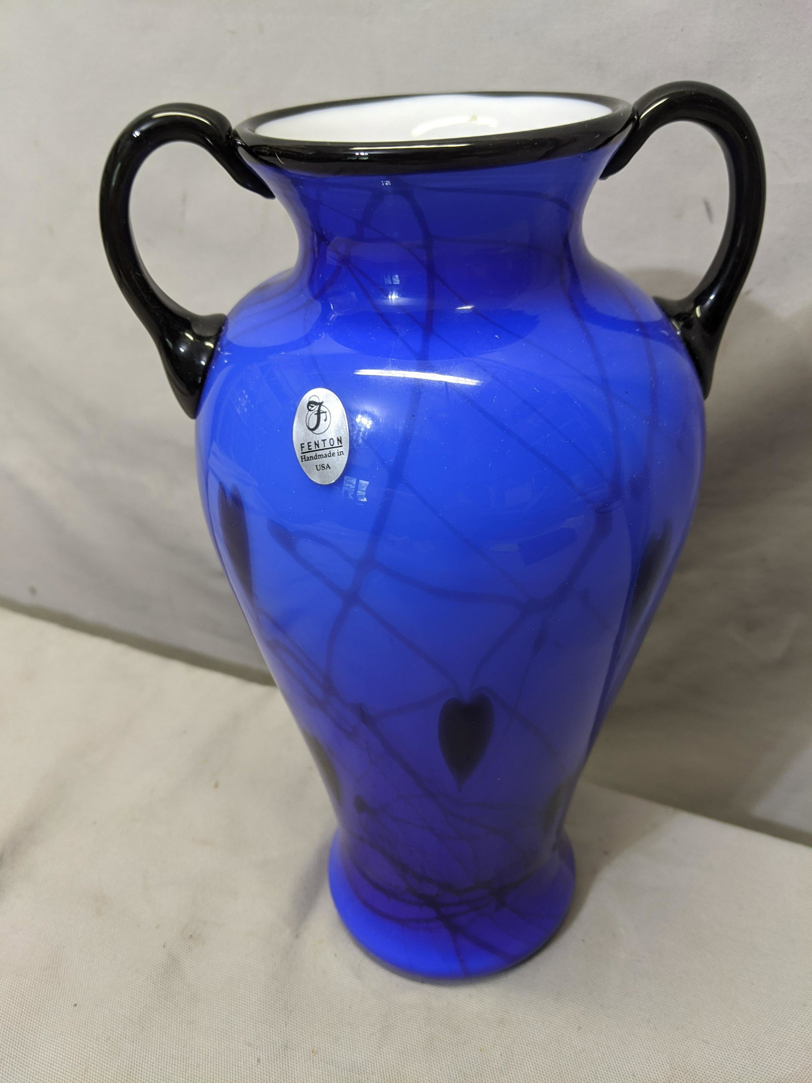 Fenton USA Blue & w/ Black Hart Art Glass Vase w/: Fenton USA Blue & w/ Black Hart Art Glass Vase w/ Handles. Measurements in inches:10 high x 5 diameter We offer in-house shipping. Item(s) will be packed after invoice is paid and shipping cost will b