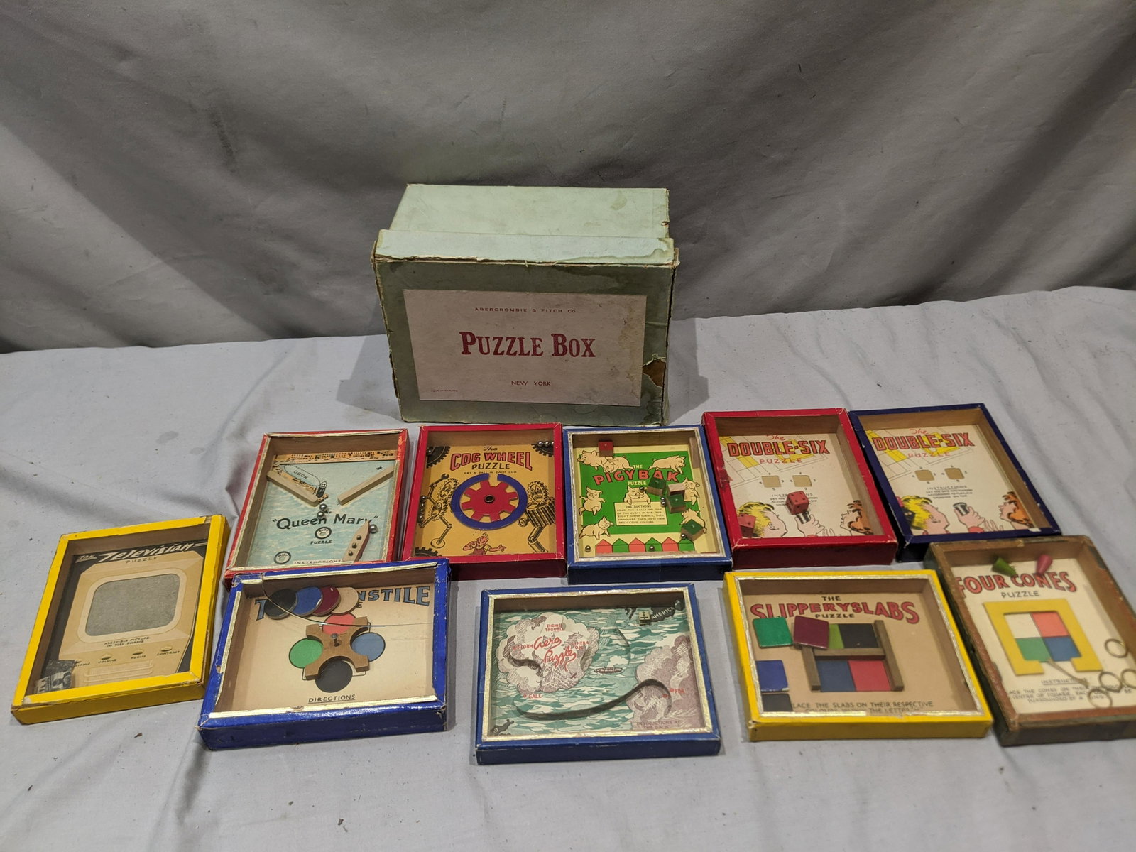 10 Abercrombie & Fitch RJ Series Dexterity Puzzles &: Set 10 Abercrombie & Fitch RJ Series Dexterity Puzzles & Box including Turnstyle, Four Cones, Double Six, Pigybak, Queen Mary, Aero Puzzle, Slipperyslabs, Cog Wheel and Television. Measurements in inc