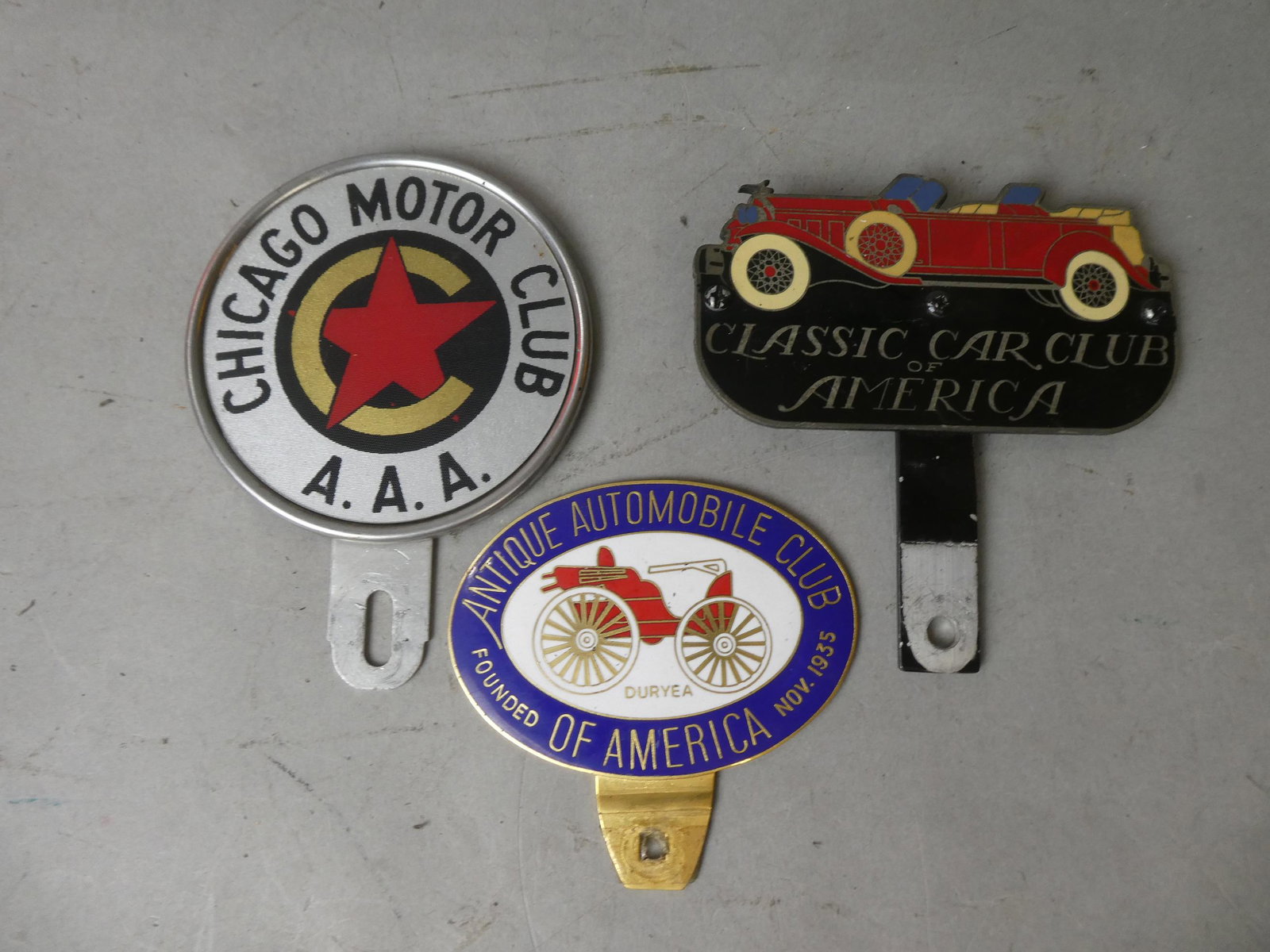 Lot 3 Vintage Car Club License Plate Toppers Porcelain: Lot 3 Vintage Car Club License Plate Toppers including Classic Car Club of America, Antique Automobile Club and Chicago Motor Club. Measurements in inches: 4 diameter, 4 x 3 and 3 x 5 Condition:Normal