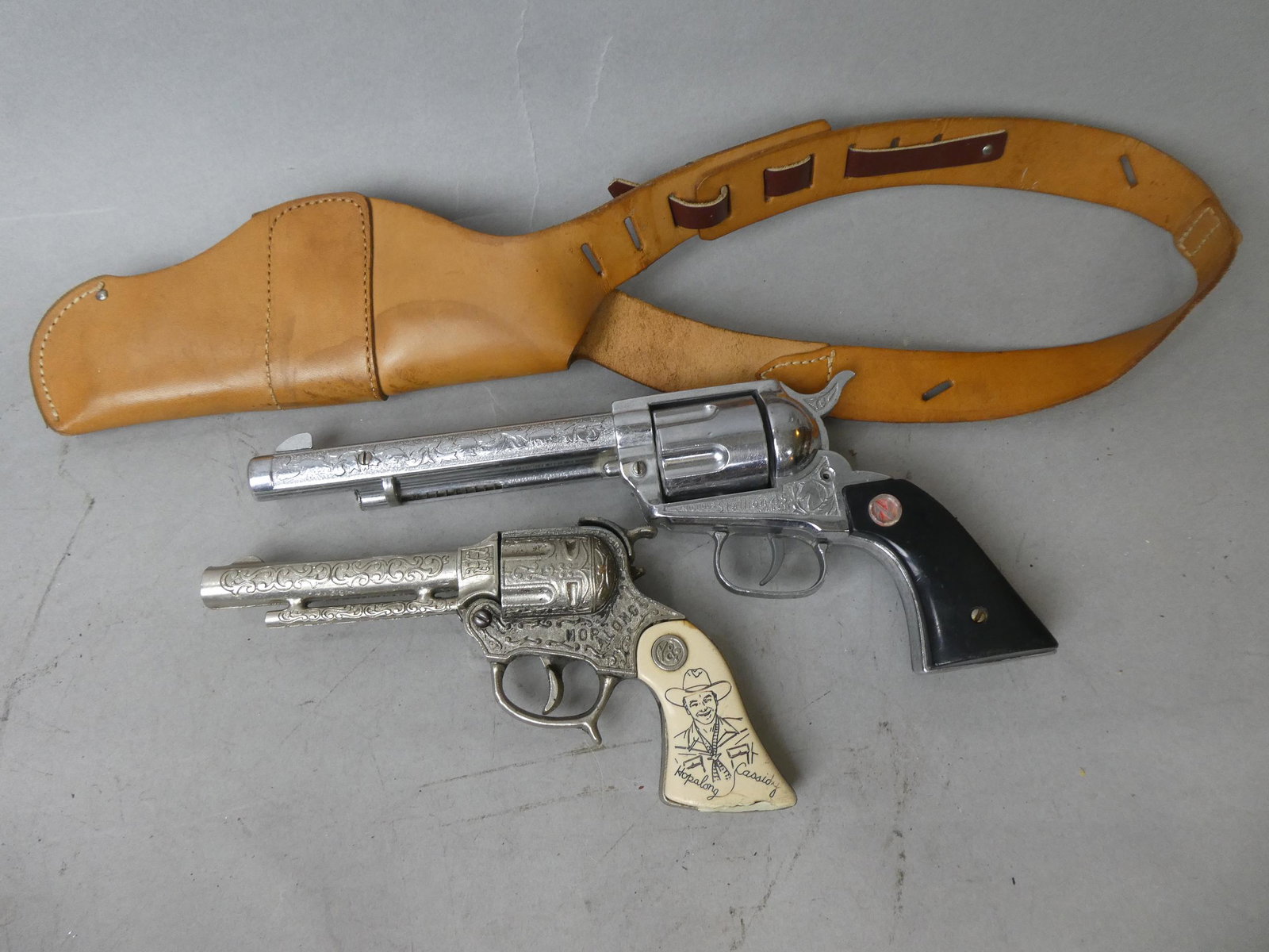 Lot 2 Capguns Hopalong Cassidy w/ Holster Stallion 45: Lot 2 Capguns Hopalong Cassidy w/ Bucheimer Holster and a Stallion 45 Mark II. Measurements in inches: 8 1/2 and 12 high Condition:Normal wear with age and use. Stallion does not fire Shipping:We offe