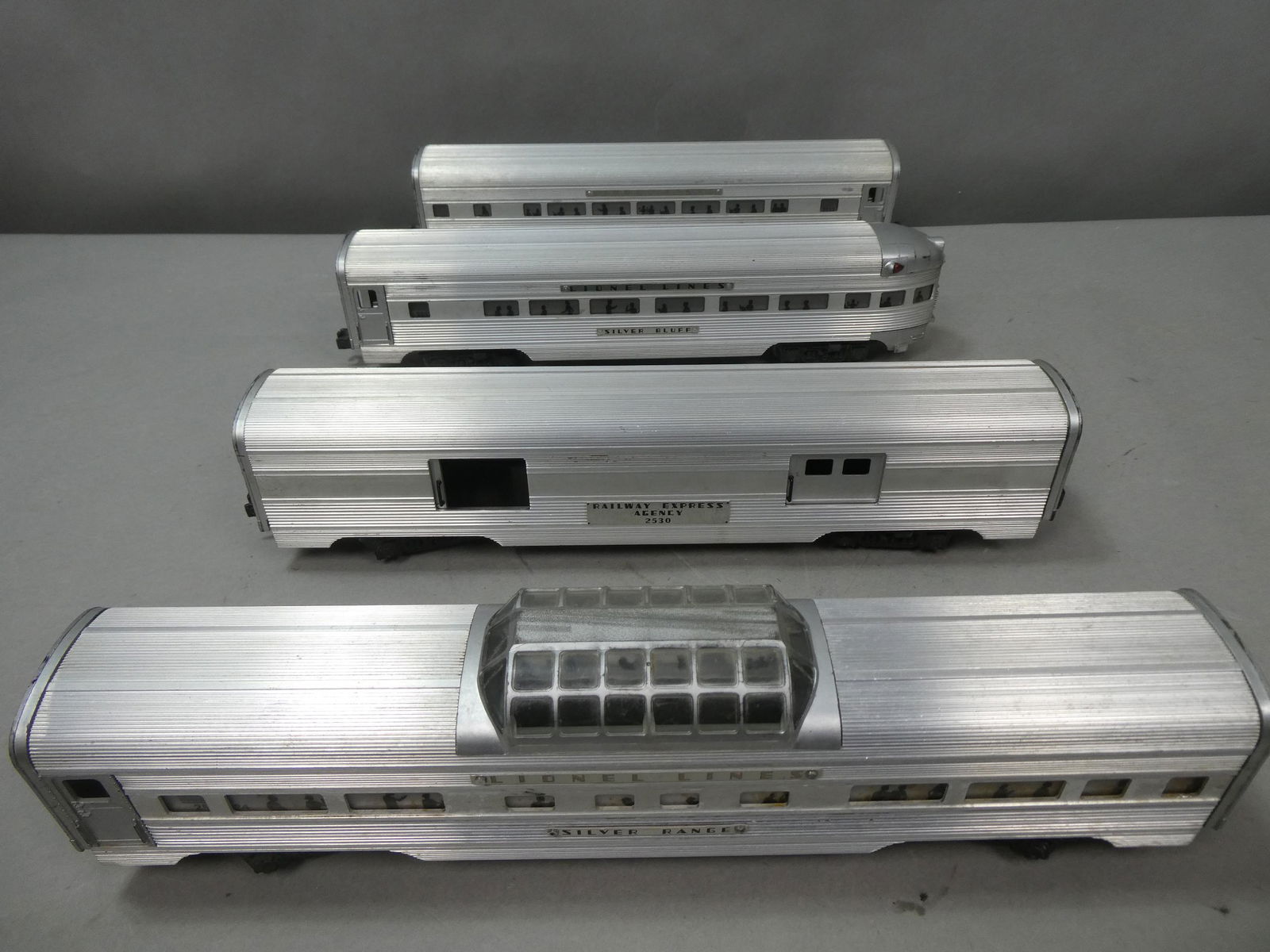 Set 4 Lionel Lines Aluminum Passenger Train Cars: Set 4 Lionel Lines Aluminum Passenger Train Cars including 2530 Railway Express Agency, 2533 Silver Cloud, 2531 Silver Bluff and 2532 Silver Range. Condition:Normal wear with age and use, Missing Lion