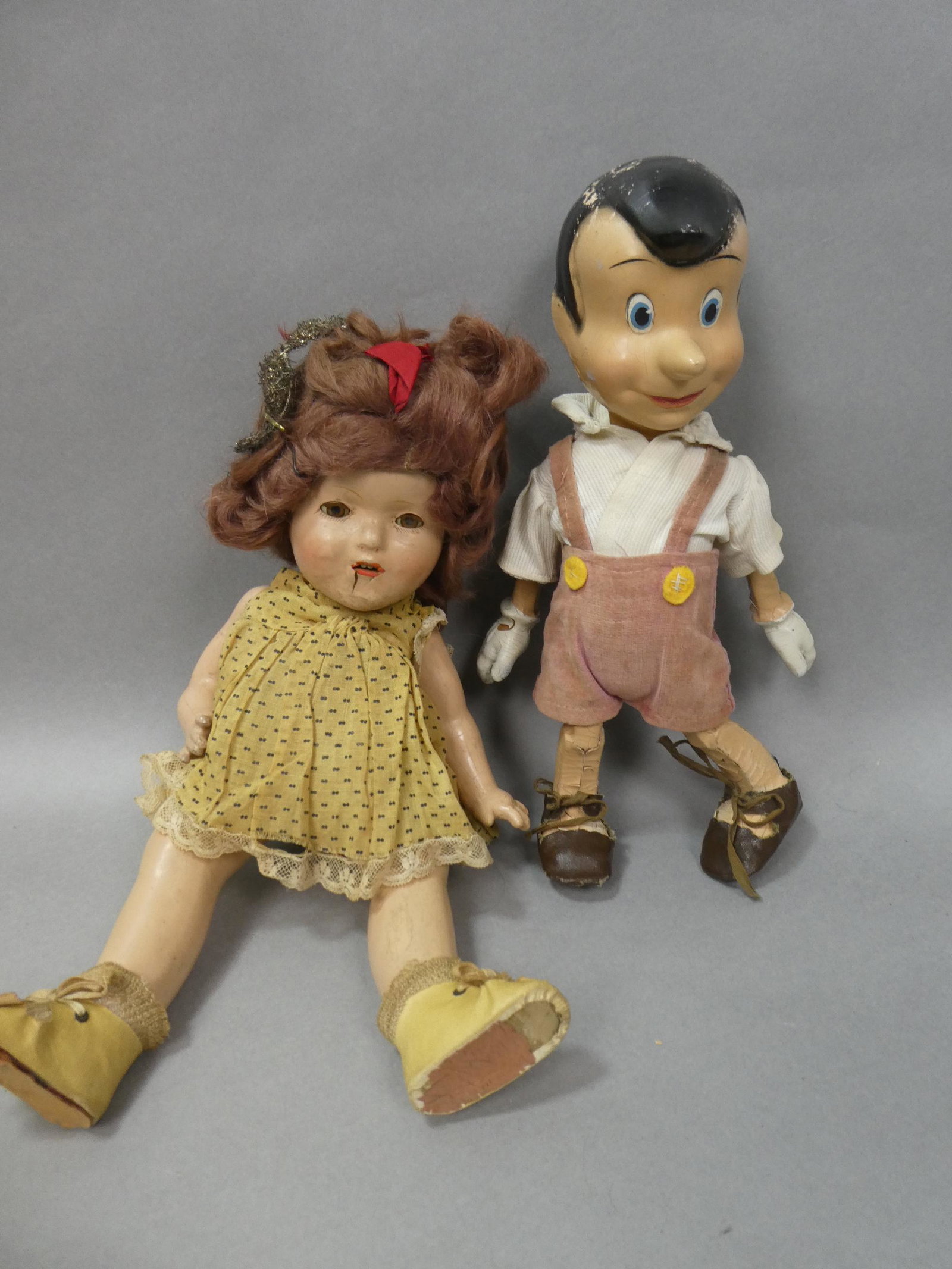 2 Early Composition Dolls Pinocchio & Shirley Temple: 2 Early Composition Dolls Pinocchio & Shirley Temple with original clothes. Measurements in inches: 13 and 15 high Condition:As found, sold as is. Show damage to both Shipping:We offer in-house shippi