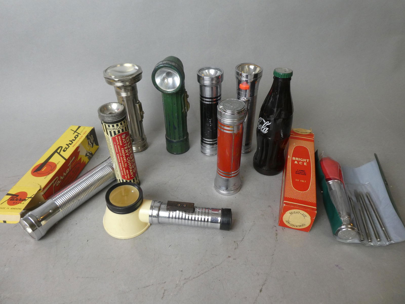 Lot 10 Assorted Flashlights Parrot Coca-Cola Bright Ace: Lot 10 Assorted Flashlights including Bright Ace new in the Box, Parrot new in the box, Coke bottle, Burgess, Magnifying glass, ABC, Warco, Royal and Gits. Measurements in inches: around 7 long Condit