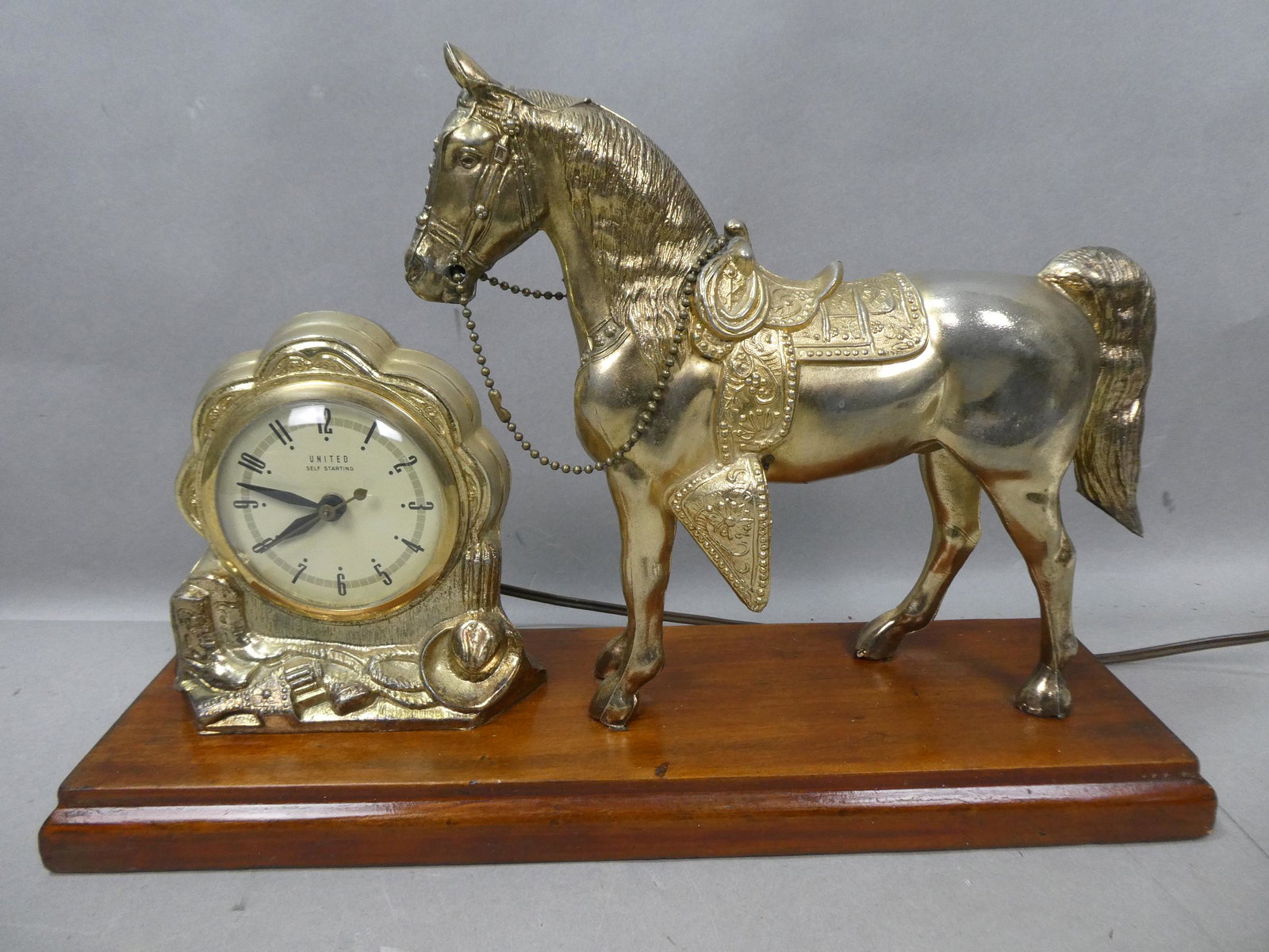 Vintage Figural Horse Gold Tone United Clock: Vintage Figural Horse Gold Tone United Clock on wood base. Measurements in inches: 5 x 17 x 12 high Condition:Minor wear with age, turns on and works Shipping:We offer in-house shipping. Item(s) will 