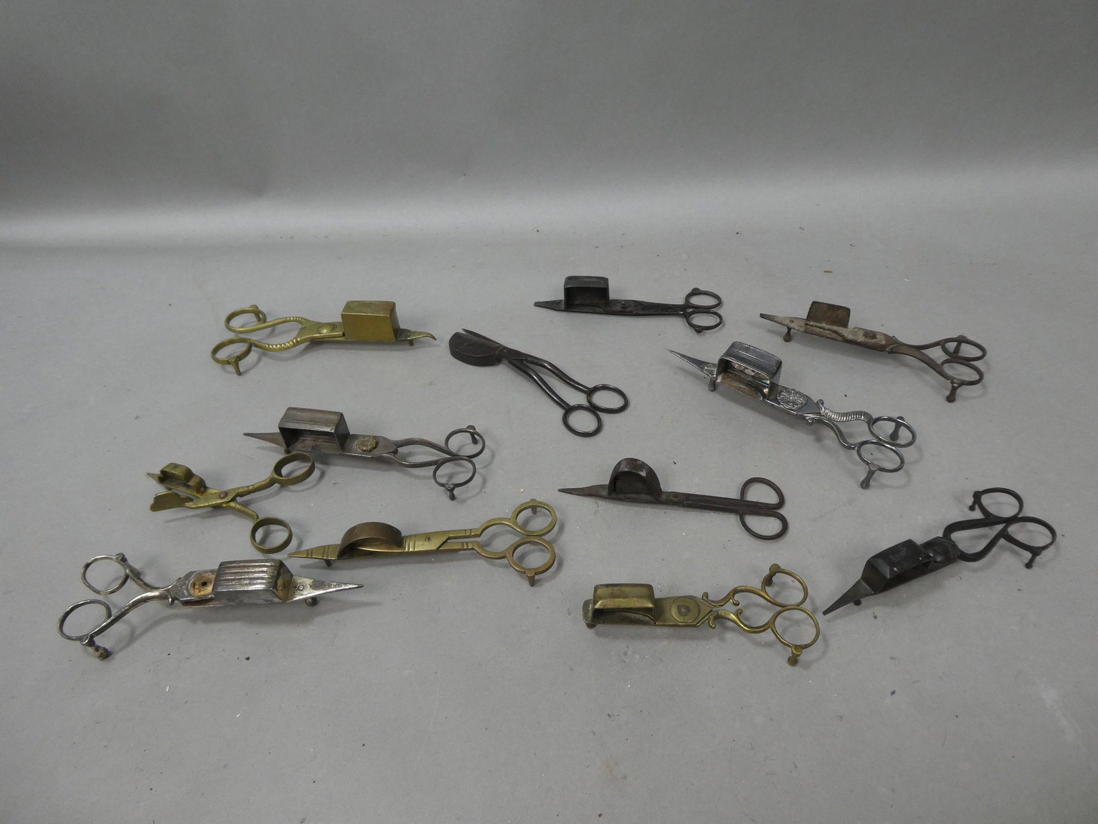 Lot 12 Antique Primitive Silver Brass & Cast Iron Candle Snuffers: Lot 12 Antique Primitive Silver Brass & Cast Iron Candle Snuffers. Condition:Normal wear with age and use, one silver is missing a pin Shipping:We offer in-house shipping. Item(s) will be packed after
