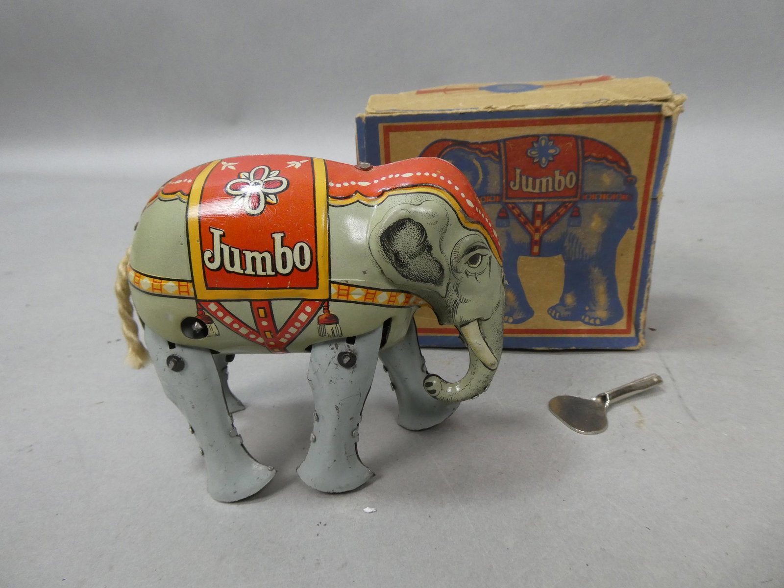 Prewar German Tin Litho Wind-up Jumbo the Elephant in Box: Prewar German Tin Litho Wind-up Jumbo the Elephant in Box with key. Measurements in inches: 4 high x 4 1/2 long Condition:Winds up and works, box shows wear Shipping:We offer in-house shipping. Item(s
