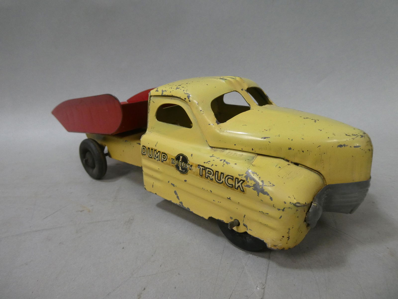 c1940's Art Deco Pressed Steel Buddy L Dump Truck: c1940's Art Deco Pressed Steel Buddy L Dump Truck with wooden wheels. Measurements in inches: 12 1/2 long Condition:Has wear and scratches with age and use Shipping:We offer in-house shipping. Item(s)