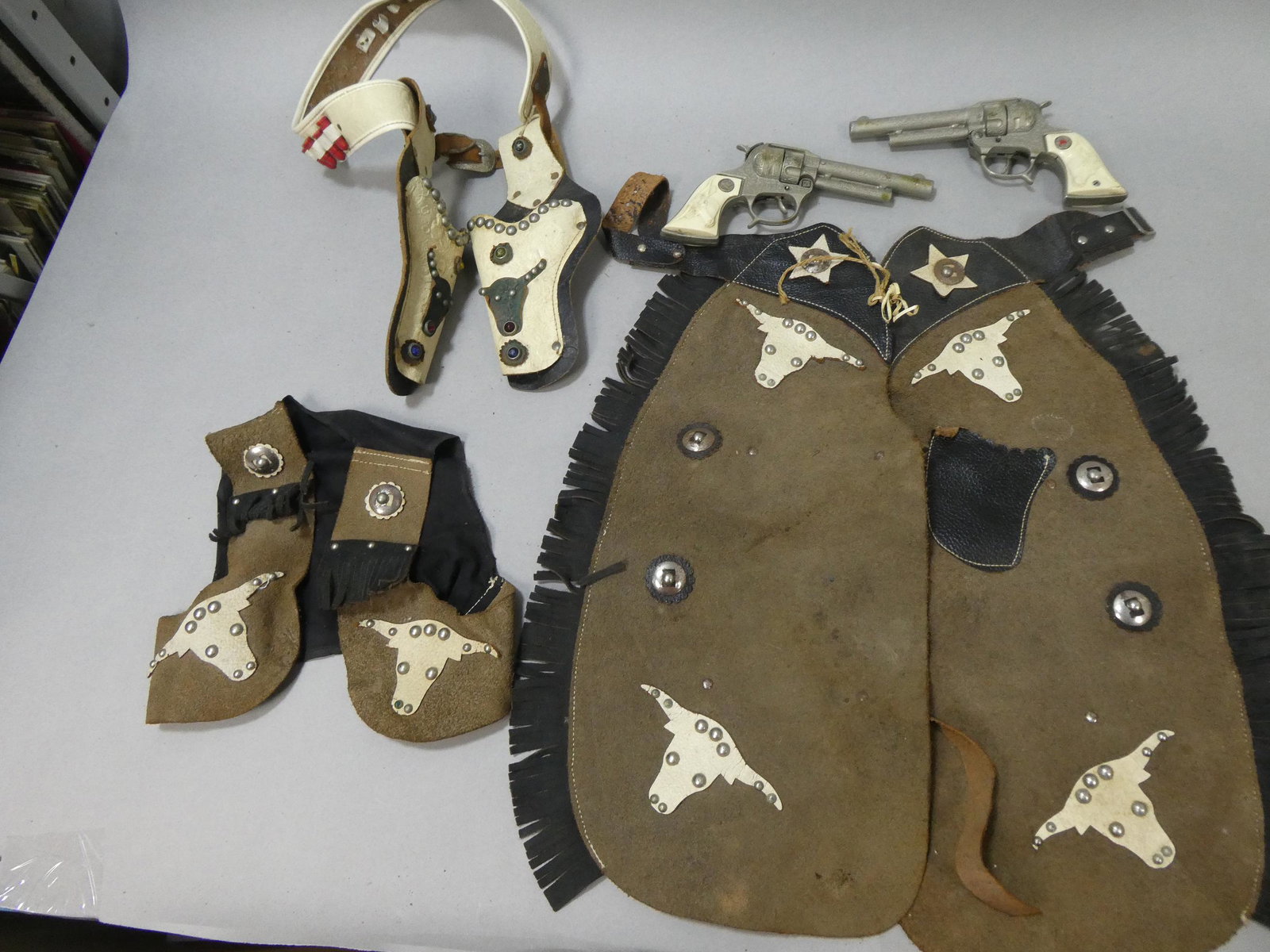 1950's Hubley Texas Jr Cap Guns Holster w/ Chaps & Vest: 1950's Hubley Texas Jr Cap Guns Holster w/ Chaps & Vest. Condition:Large piece of grip on one gun is missing, All items shows wear with age and use Shipping:We offer in-house shipping. Item(s) will be