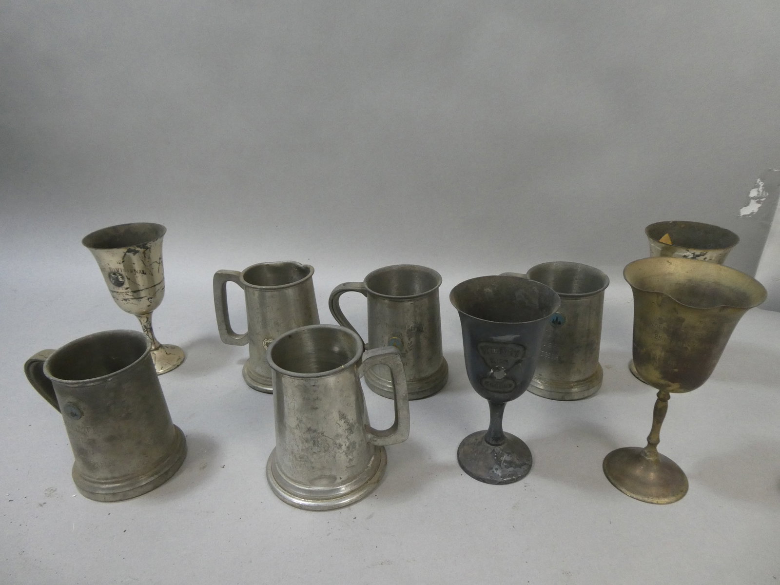 Lot 9 1960-70's Silver Plate & Pewter Racing Trophy Mugs & Wine Glasses: Lot 9 1960-70's Silver Plate & Pewter Racing Trophy Mugs & Wine Glasses. Condition:As found, well worn with dings,scratches etc Shipping:We offer in-house shipping. Item(s) will be packed after invoic