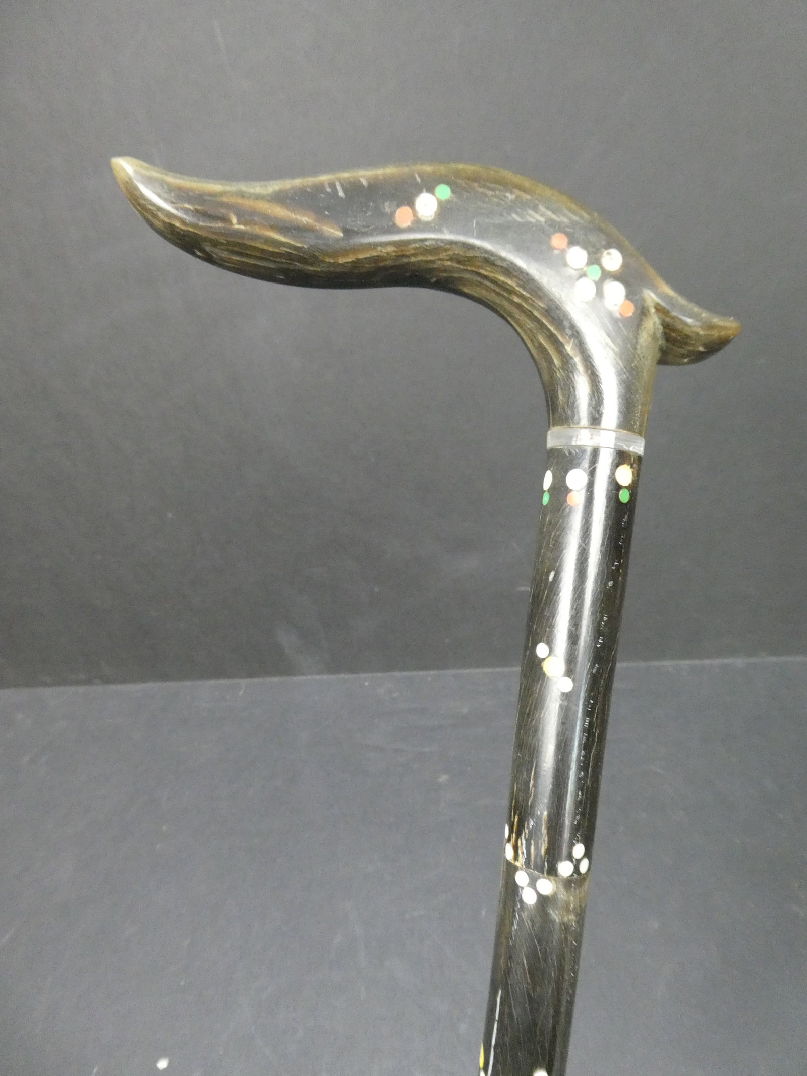 Vintage South American Carved Black Horn Cane: all black horn cane with 12 six sided segments on a steel core and a 4 3/4 in. wide and 2 in. high curved handle and embellished by various tiny colored inlay. It is from the 1920's, most likely from 