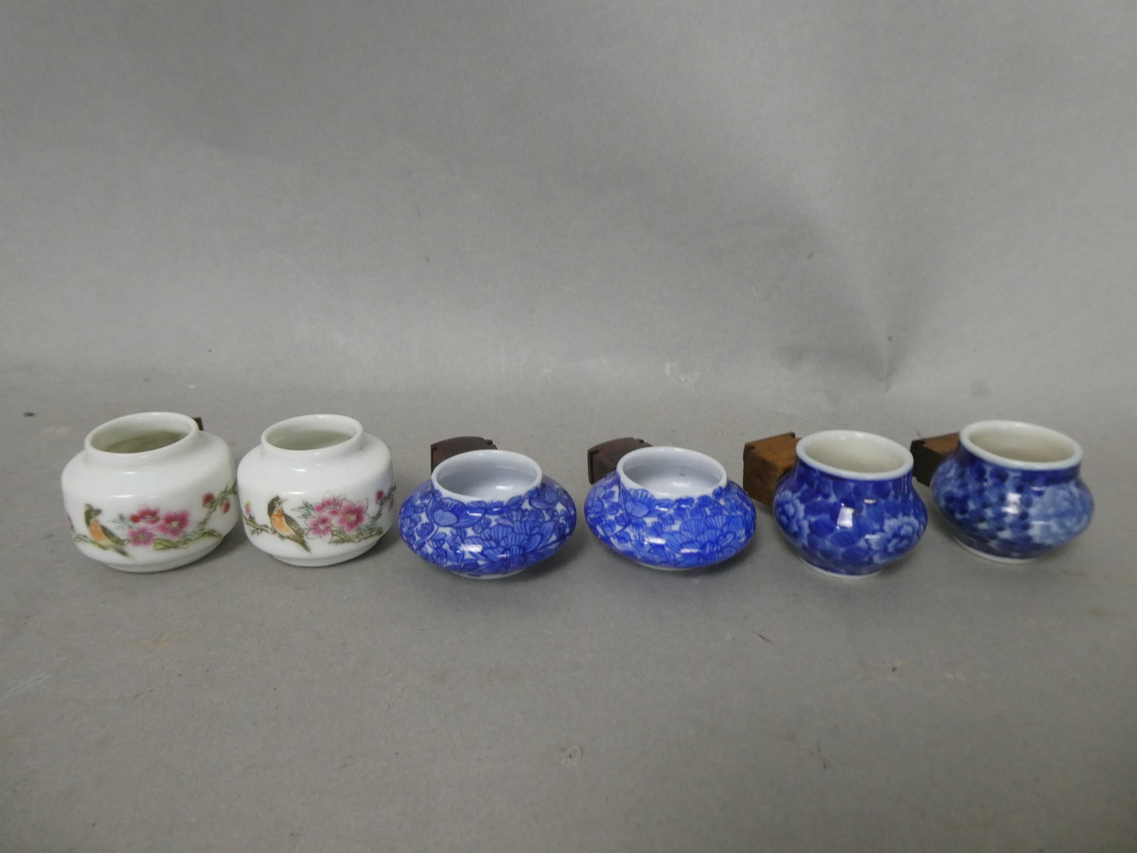 1990's Chinese Group of 3 pairs porcelain bird feeders: Assortment of porcelain feeders, some in blue and white designs, the other painted porcelain in flower designs. Measurements in inches: average 1.75" including wood attachment x 1" H Condition:Good wi