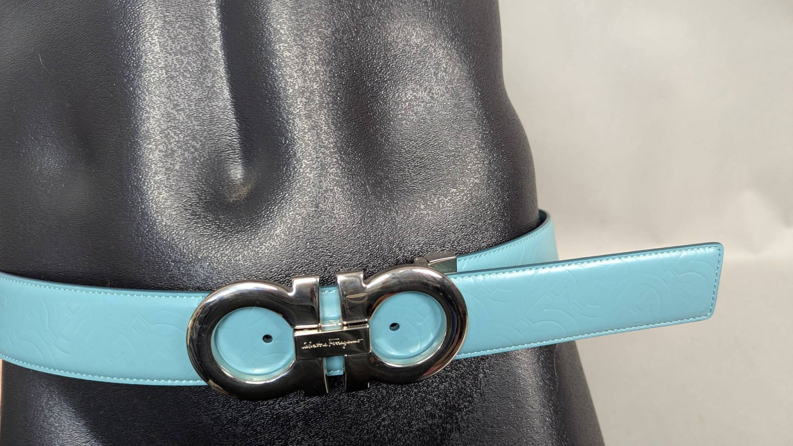 Salvatore Ferragamo 42 Embossed Leather Belt with Silver-Tone Buckle: Salvatore Ferragamo belt measuring 42 inches long and 1/2 inch wide, featuring embossed light blue leather with a signature Gancini design. The silver-tone buckle is engraved with the brand name and h