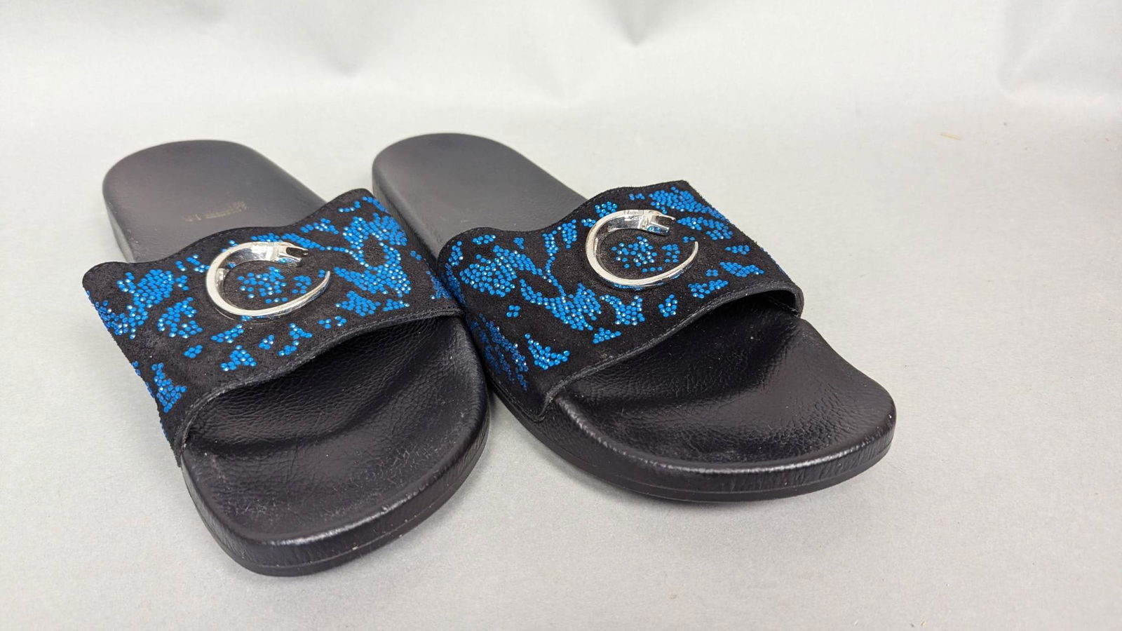 Robert Cavalli Black and Blue Mens Slides with Snake Detail: Robert Cavalli Men's open-toe slides featuring a black base with a blue leopard-patterned strap adorned with a silver-toned snake emblem. The insole is textured black, with branded gold lettering. Sol