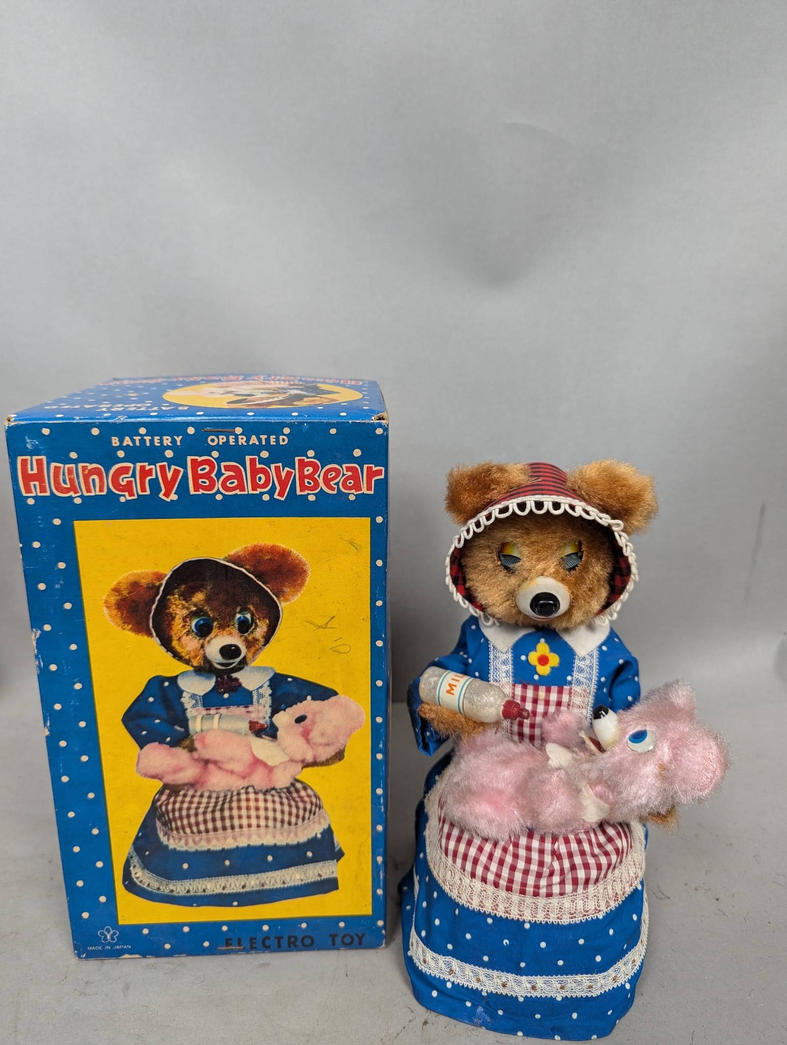 Battery-Operated Hungry Baby Bear Electro Toy with Original Box: Battery-operated Hungry Baby Bear Electro Toy featuring a bear in a blue polka dot outfit feeding a pink baby bear with a milk bottle. Includes the original printed box. Not in working condition. Box 