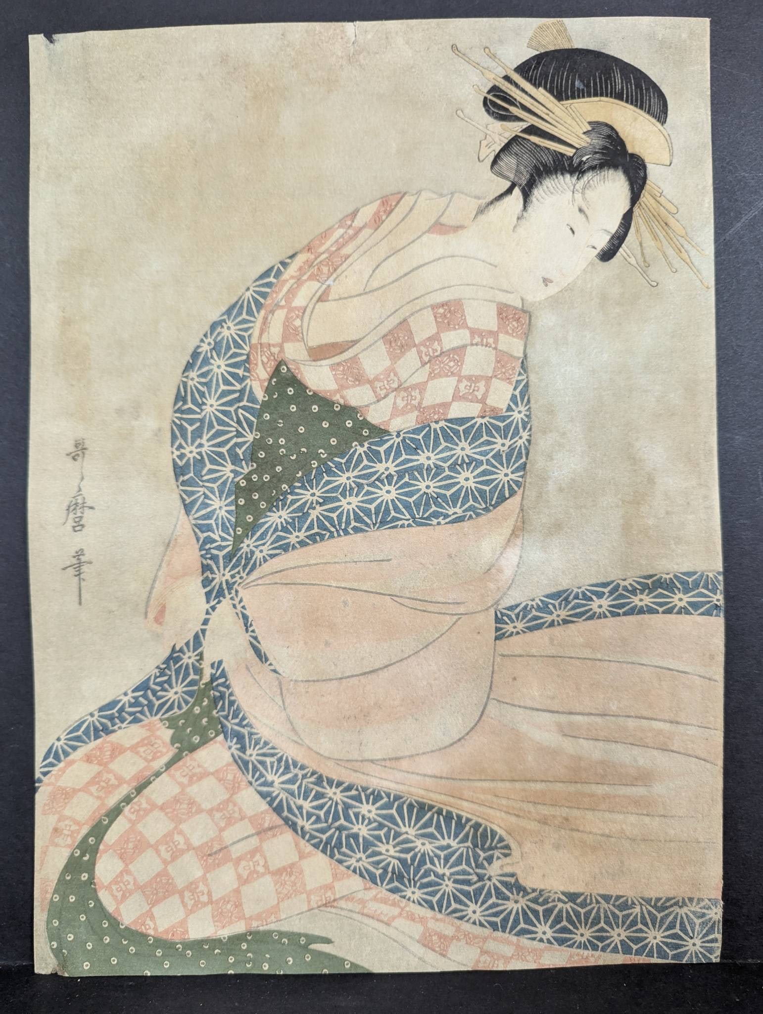 Reproduction of Utamaro Japanese Woodblock Print of Woman: Reproduction Japanese woodblock print by Utamaro measuring 10 x 13.5 inches. Features a depiction of a woman in traditional attire with intricate patterns. The piece shows some wear and aging consiste
