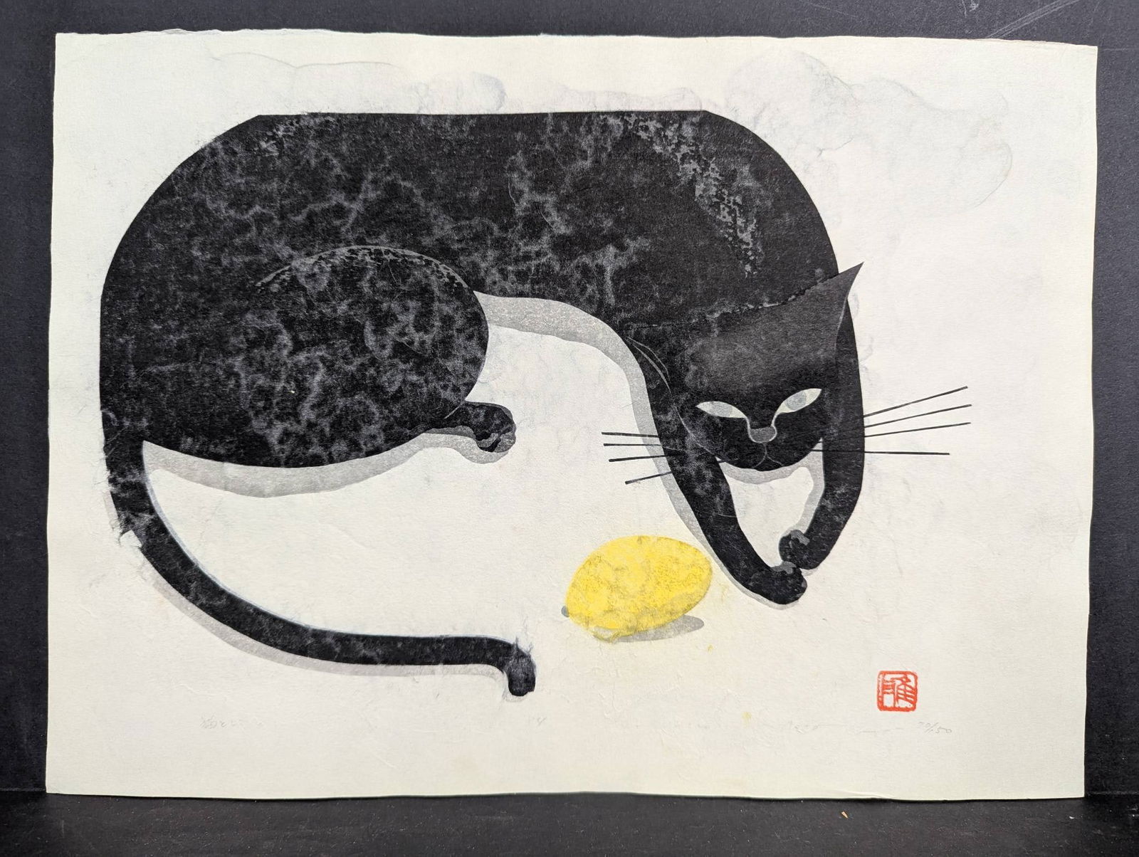 Masao Ido Japanese Woodblock Print Cat and LemonÂ? 1981: Woodblock print titled "Cat and Lemon" by Japanese artist Masao Ido (1945-2016). Created in 1981 it features a black cat interacting with a lemon evoking a nostalgic vision of Japan. Signed in pencil