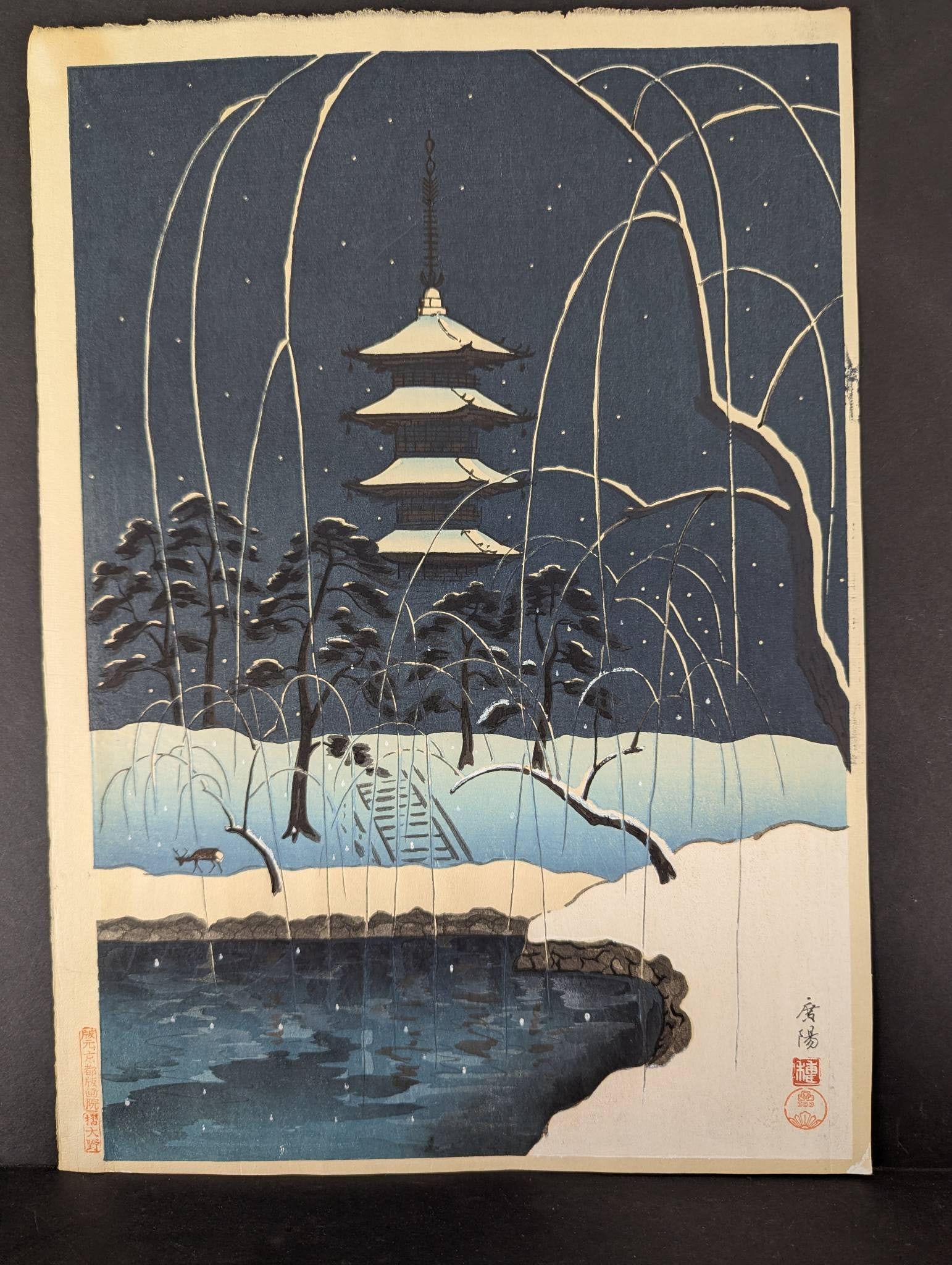Japanese Woodblock Print Pagoda in Nara Winter by Koyo: Japanese woodblock print titled Pagoda in Nara Winter by artist Koyo. The artwork depicts a serene, snowy scene featuring a pagoda and willow branches in a winter setting, with delicate snowflakes fal