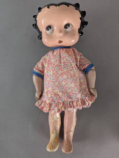 1930s Betty Boop Composition Doll With Original Features: A 1930s Betty Boop composition doll featuring its original body and face paint. The doll has a distinct painted face with big eyes, black painted hair with curls, and a small red mouth. It is dressed