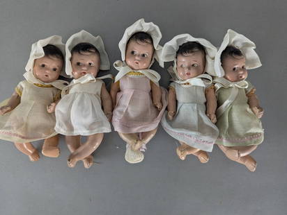 Lot of Five Composition Baby Dolls with Bonnets and Dresses: Lot of five composition dolls, each dressed in lightweight vintage-style dresses in varying pastel colors, with matching bonnets tied with ribbons. The dolls measure approximately 7 high x 4 wide x 3