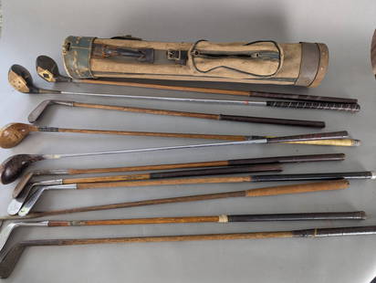 Collection of Vintage Hickory Shaft Golf Clubs with Carry Bag: A collection of vintage golf clubs featuring hickory shafts and wooden heads, along with a canvas and leather carry bag. The set includes various club types, including irons and woods, with makers'