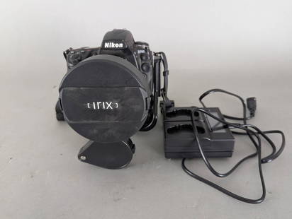 Nikon D700 DSLR Camera with Irix 11mm Lens and Accessories: Nikon D700 digital SLR camera featuring an Irix 11mm f/4 wide-angle lens. Includes a Kastar LCD dual smart battery charger and a camera grip attachment. The camera, lens, and accessories exhibit signs