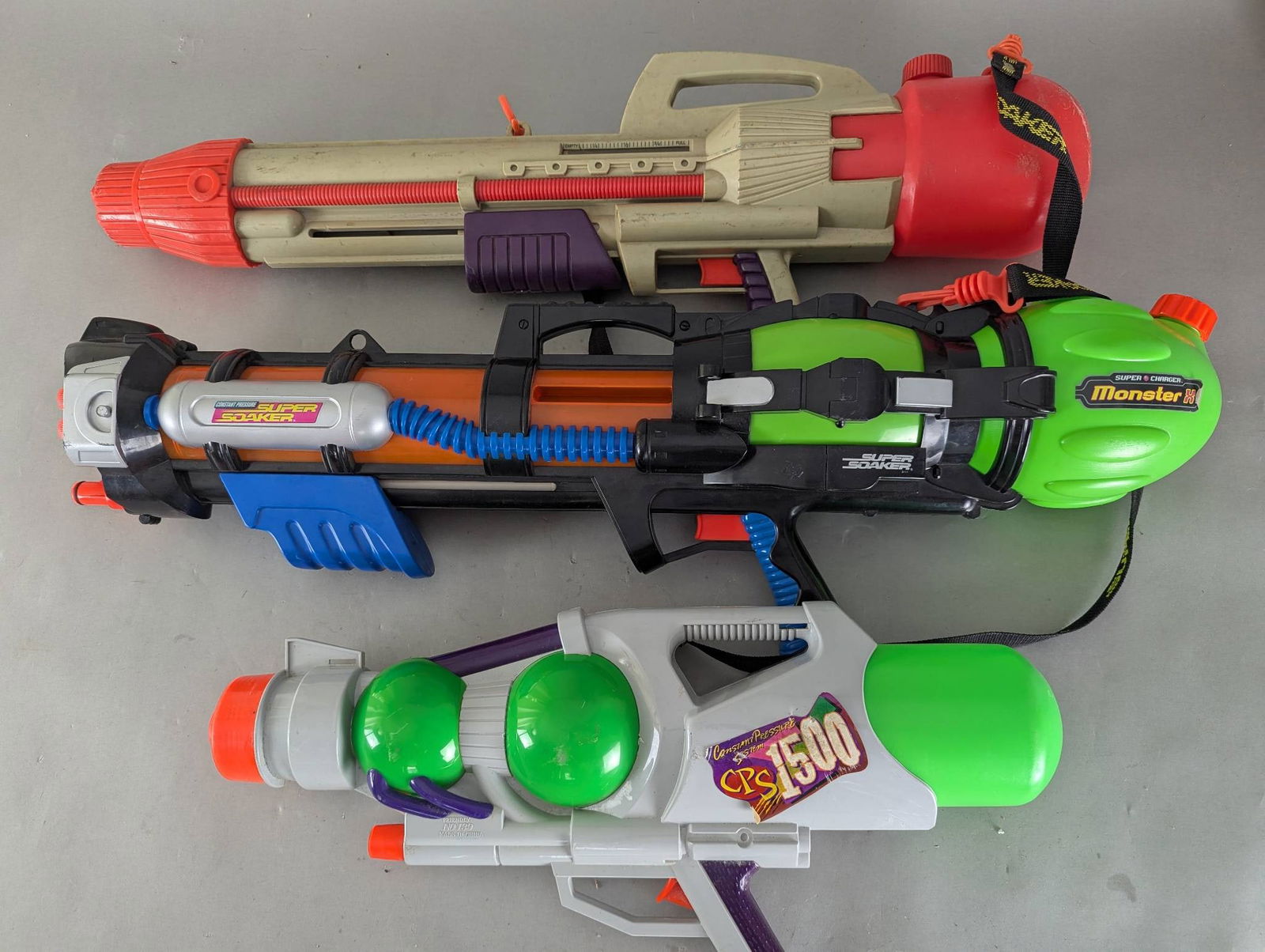 Three Super Soaker Water Guns Including Monster XL: Three vintage-style water guns includes one branded as Super Soaker Monster XL, one labeled as Super Soaker Constant Pressure, and one marked Friendly No 139. The Super Soaker branded items are noted