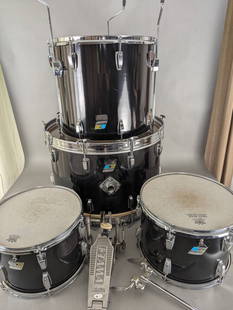 4 Piece Ludwig 1970's Wood Drum Set with Tama Pedal: Ludwig 1970's Wood set in black, featuring four drums of various sizes: 17 high x 25 deep x 25 wide, 18 high x 18 diameter, and two 11 x 15 diameter. The set includes a Tama bass drum pedal. Used cond