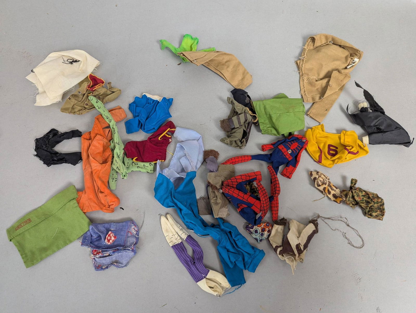 Vintage 1060-70's Superhero and Gi Joe Action Figure Clothes: Superhero and Gi Joe action figure clothing items. Includes a variety of costumes and accessories in various colors and patterns. One specific item measures 3 inches in height, 1 inch in width, and 2