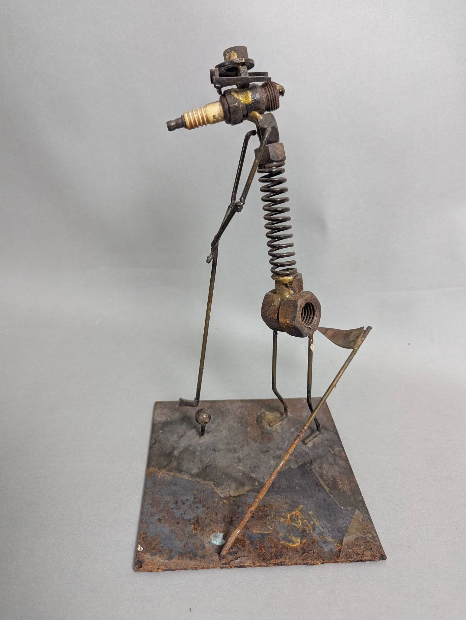The Ugliest Golfer Sculpture by Richard Cooley, Welded Metal Art: Original vintage scrap metal sculpture titled The Ugliest Golfer by artist Richard Cooley. Constructed from salvaged metal materials such as nuts, bolts, springs, and a spark plug forming the head, it