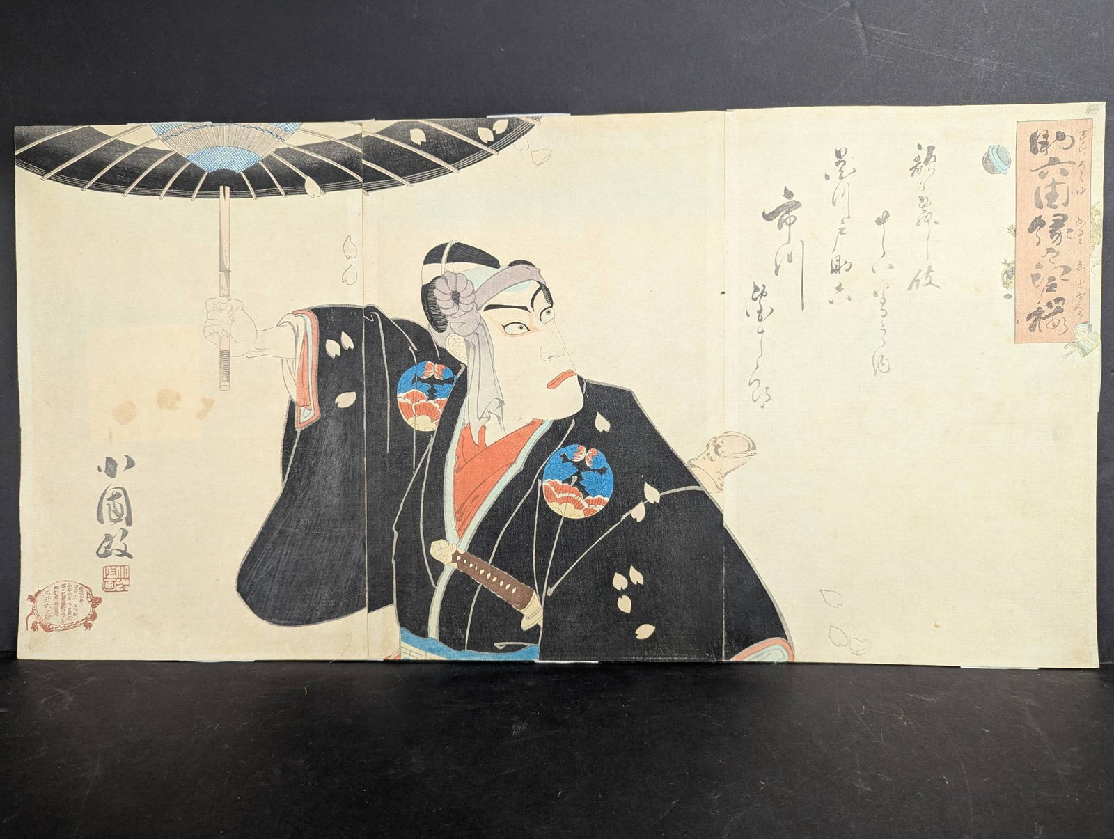 Japanese Woodblock Print of Actor with Umbrella Triptych 19th Century: A Japanese woodblock print triptych featuring an actor with an umbrella, attributed to the 19th century. The artwork measures 28 in height and 14 in width. The woodblock print exhibits notable signs o