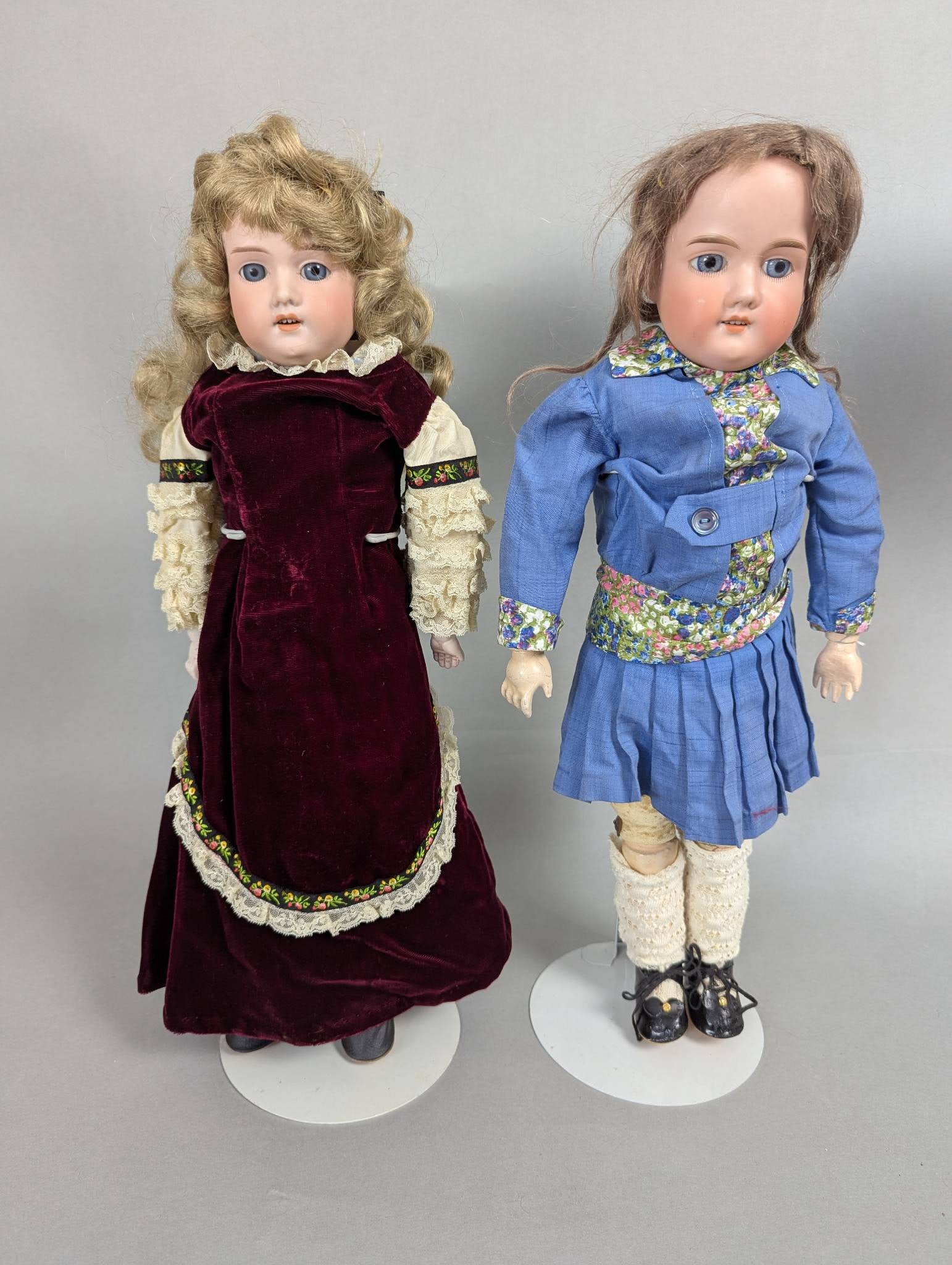 Armand Marseille Bisque Head Dolls in Dresses: Armand Marseille dolls featuring bisque heads and dressed in period-style outfits. One doll measures approximately 19 inches in height, 8 inches in width, and 3 inches in depth, while the other measur