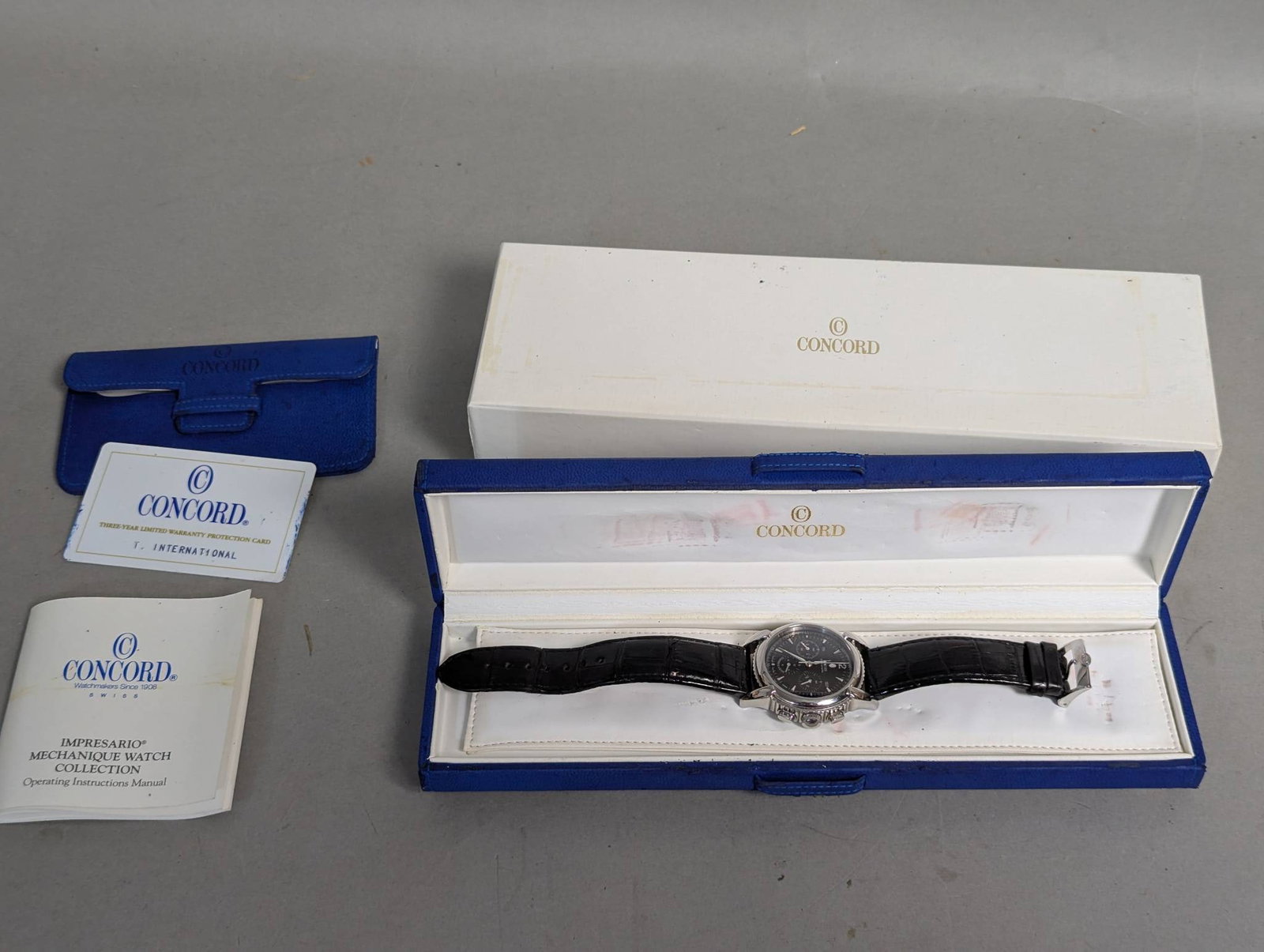 Concord Impresario Chronometer Watch with Box and Documents: Concord Impresario Chronometer watch featuring a mechanical movement, a black leather strap, and a detailed display with day, date, and seconds subdials.1 1/2 inches across the watch face. The watch c