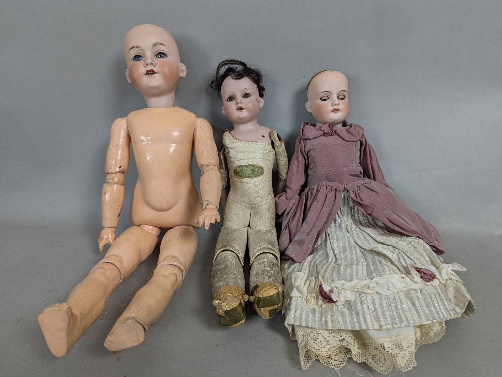 Three Antique Bisque Head Dolls Including Armand Marseille: Three antique bisque head dolls, including one marked Armand Marseille, Germany. The first doll measures approximately 21 inches high, with a fully jointed composition body and open and close eyes. Th