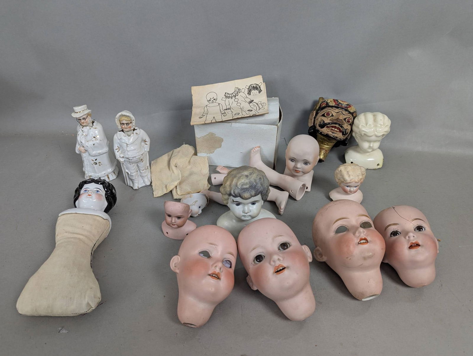 Antique Doll Heads and Parts Including Two Bobbleheads: Antique lot featuring doll heads and parts primarily made of china and bisque, along with two bobblehead figurines. The lot includes multiple bisque doll heads with painted features, various sizes of