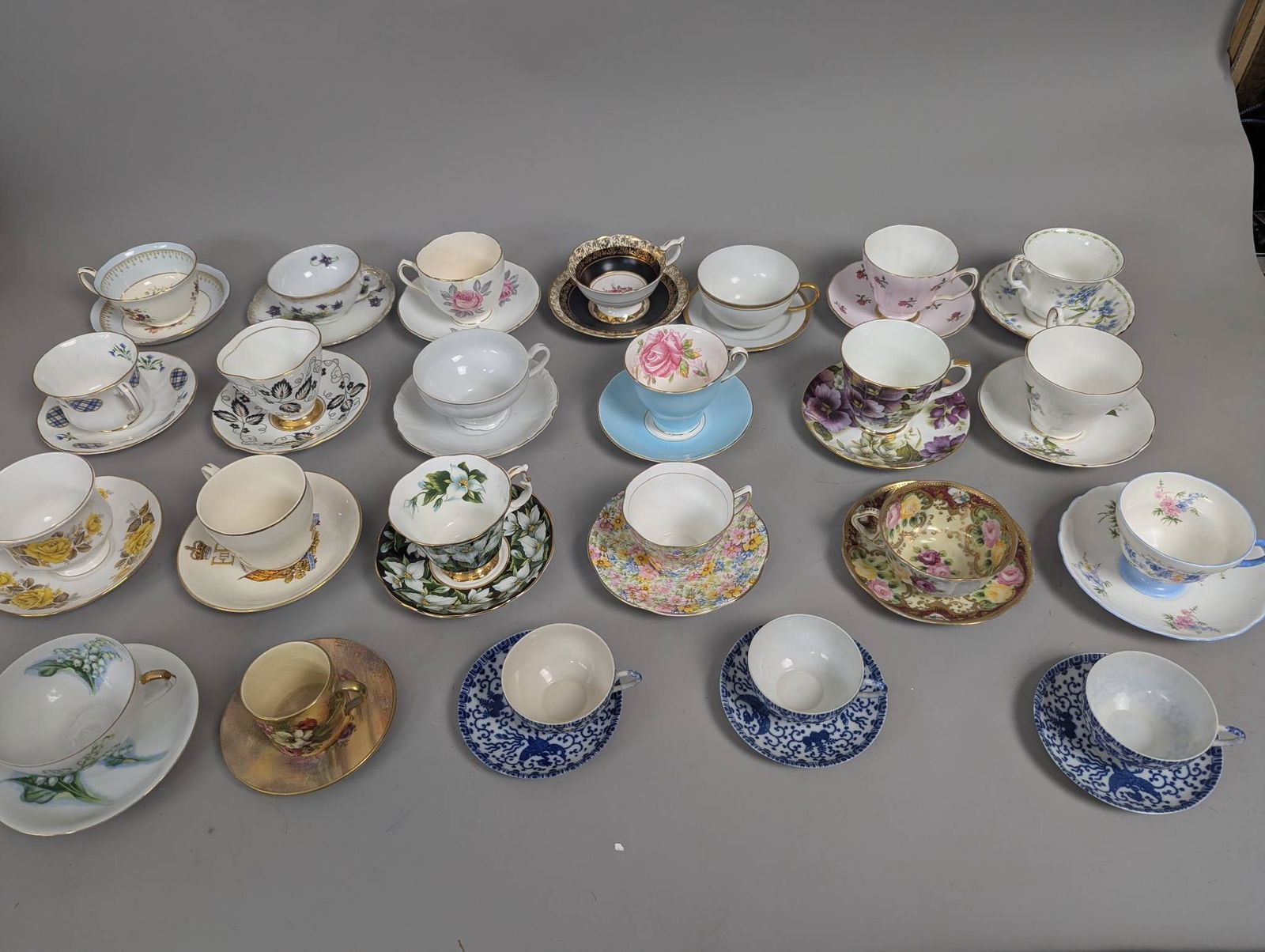 25 Assorted Antique Cups and Saucers: 25 assorted antique cups and saucers, featuring a variety of patterns, styles, and floral motifs. The collection comprises a mix of bone china and porcelain pieces, with gilded detailing and intricate