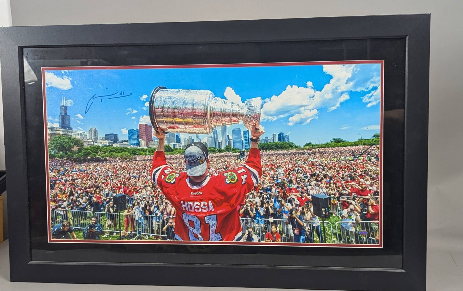 Framed Marian Hossa Chicago Blackhawks Stanley Cup Victory Parade Print: Framed print depicting Marian Hossa of the Chicago Blackhawks holding the Stanley Cup aloft during a victory parade and rally in Chicago. This image celebrates one of the Blackhawks' Stanley Cup champ