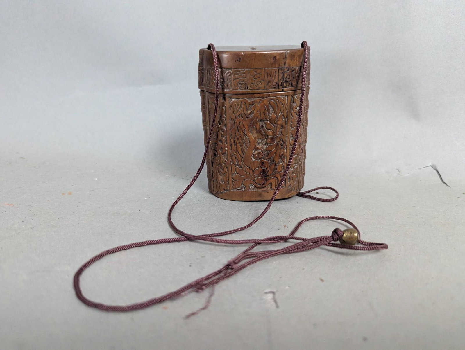 Japanese Carved Wooden Inro with Traditional Motifs and Cord: Japanese carved wooden inro measuring 3 1/2 inches high, 2 1/2 inches wide, and 1 1/2 inches deep. This traditional Japanese accessory, typically used for carrying small personal items like medicines 