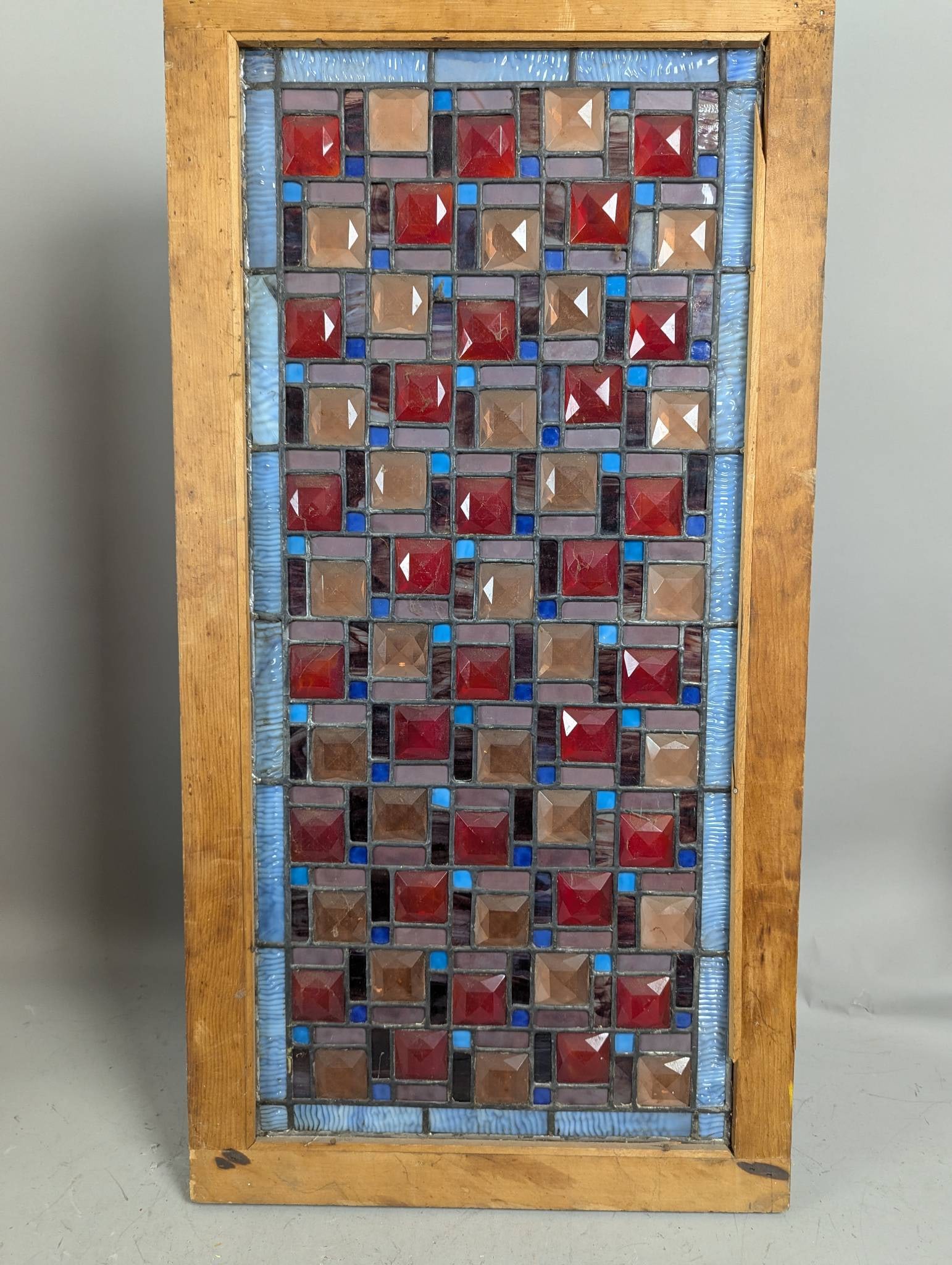 Antique Leaded Stained Glass Window with Gold and Red Jewels: Antique leaded stained glass window featuring square gold and red large jewels. The piece includes intricate stained glass detailing with blue, red, and amber hues complemented by clear and textured g