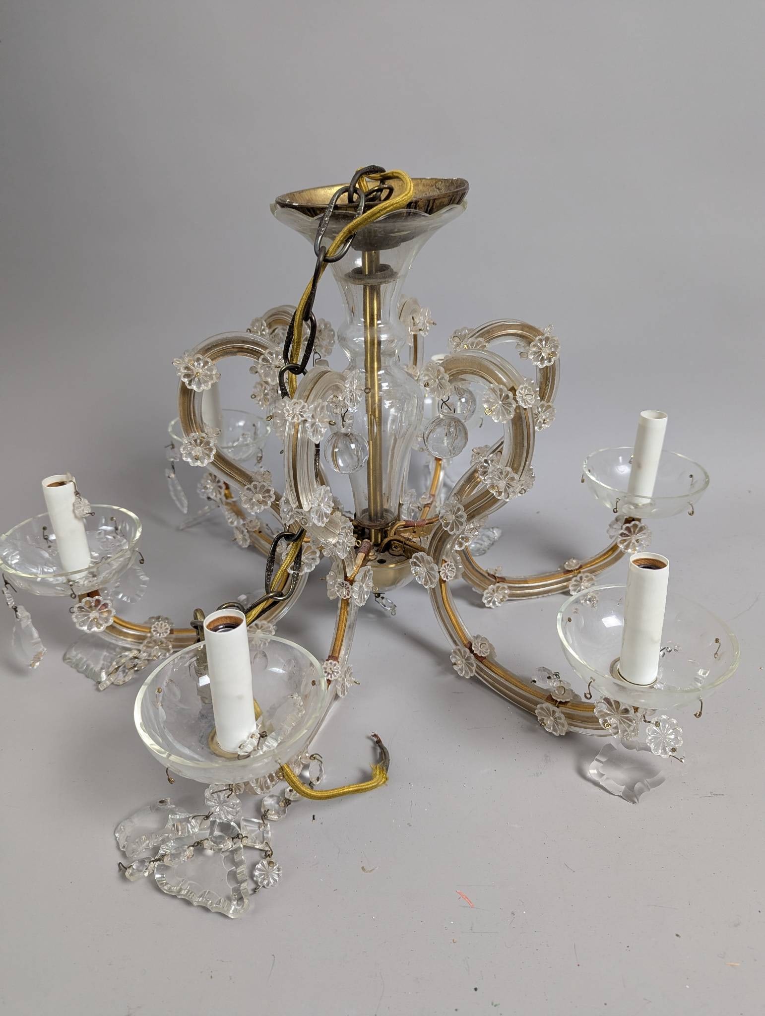 Maria St Clair Glass & Metal Chandelier w/ PrismsÂ : Maria St Clair chandelier featuring a glass and metal framework adorned with floral and crystal-like accoutrements. Measures 14 high x 22 across. Designed for six candle-style light bulbs. Several pri