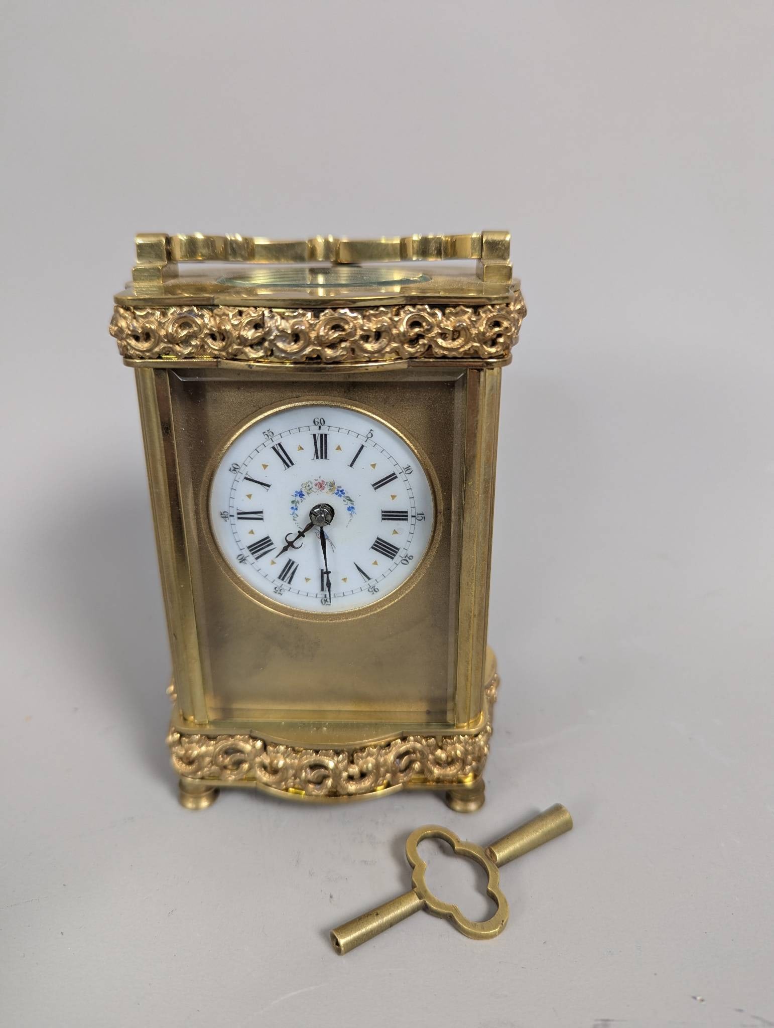 French Victorian Ornate Brass Carriage Clock Circa 1880: French Antique Victorian carriage clock crafted from ornate brass, dating to approximately 1880. It measures 5 inches high, 3 inches wide, and 2 1/2 inches deep. Features an enamel dial with Roman num