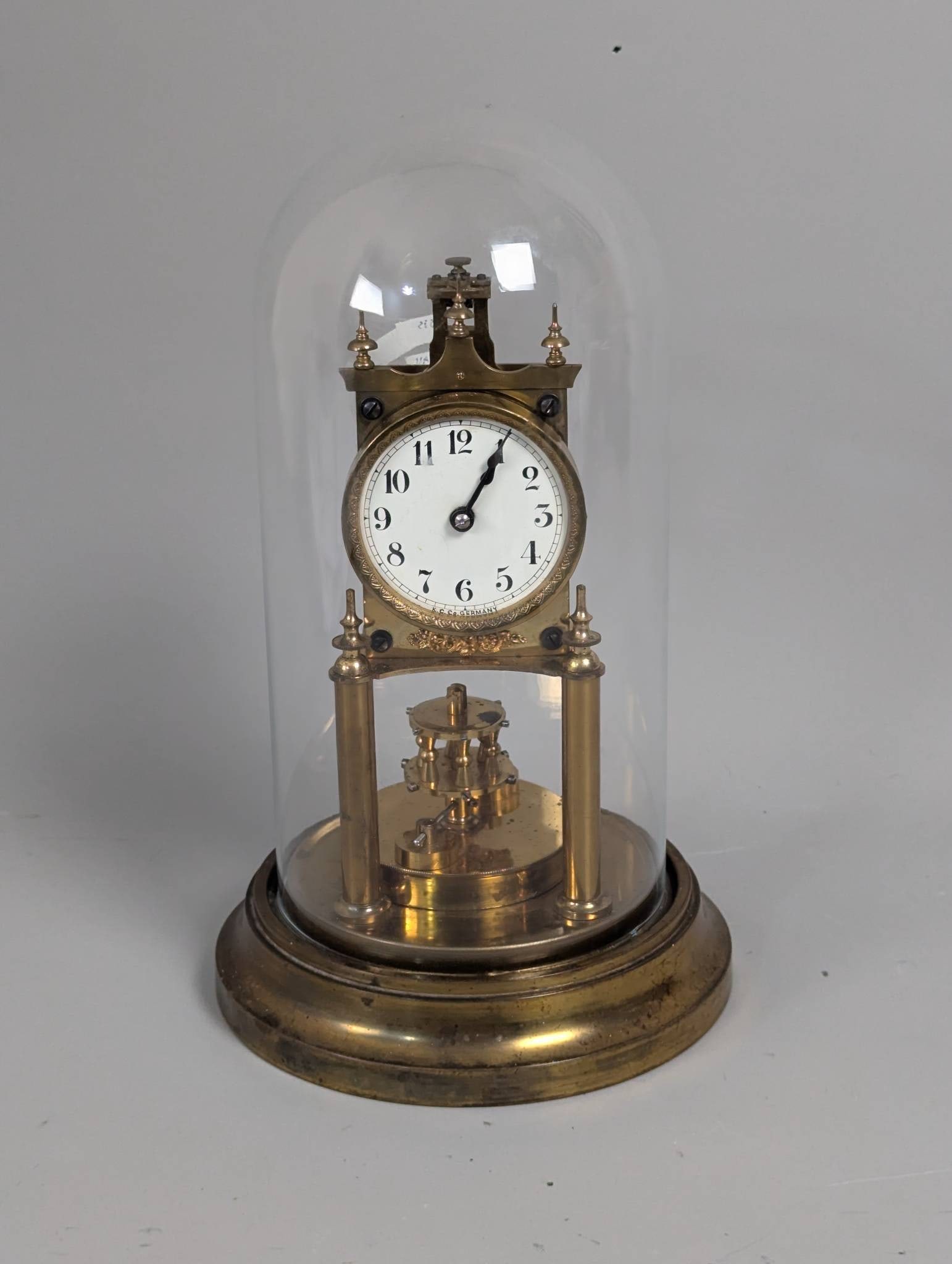 Gustav Becker 400-Day Torsion Pendulum Clock: Gustav Becker 400-day torsion pendulum clock, also referred to as an anniversary clock, featuring a brass construction with visible wear. The clock measures 13 in high and 7 in diameter. It has an ena
