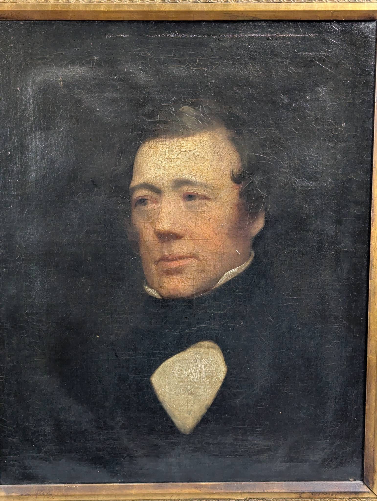 Oil on Canvas Portrait of a Gentleman in Ornate Giltwood Frame: An antique oil on canvas portrait of a gentleman, likely from the 19th century. Painted in the English School style, the work depicts a seated gentleman in a formal pose, dressed in a dark coat and hi