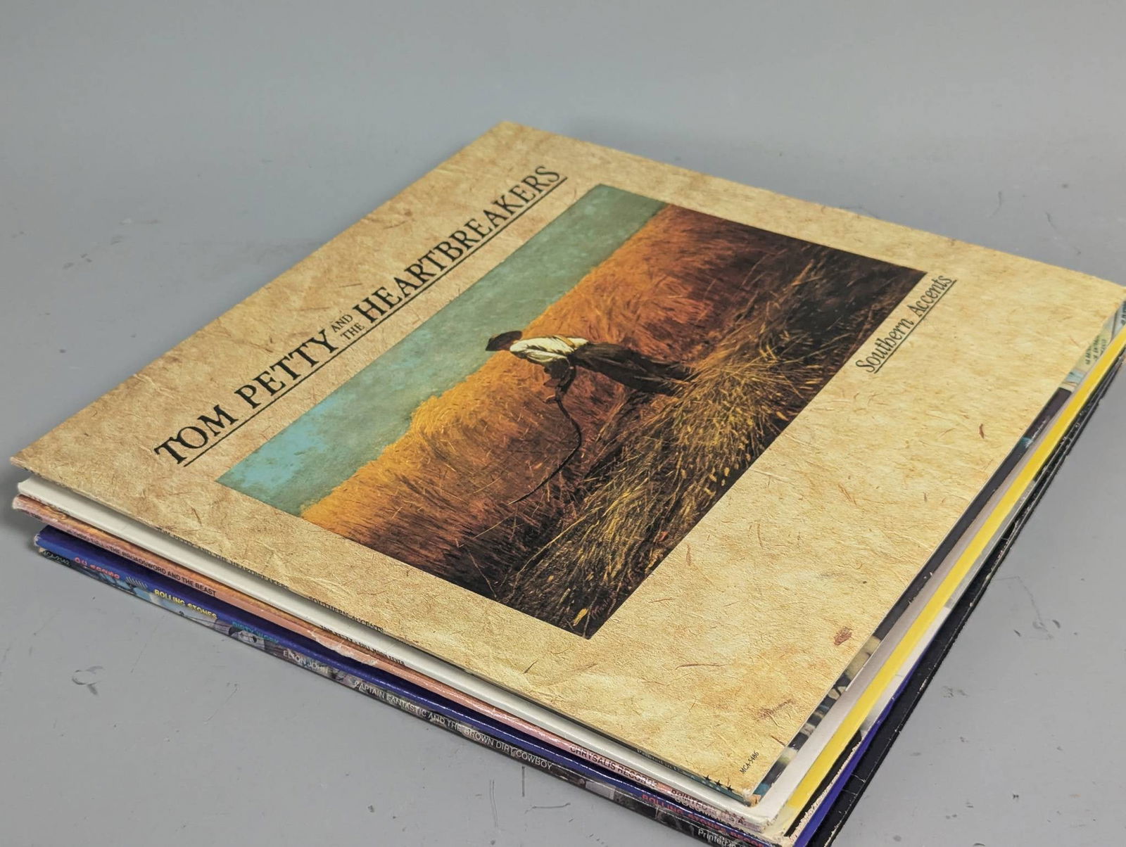 8 Rock and Pop Vinyl Records by Various Artists: 8 vinyl records measuring approximately 12 inches high, 12 inches wide each. Includes titles by Tom Petty and The Heartbreakers such as Southern Accents and Hard Promises, along with other notable alb