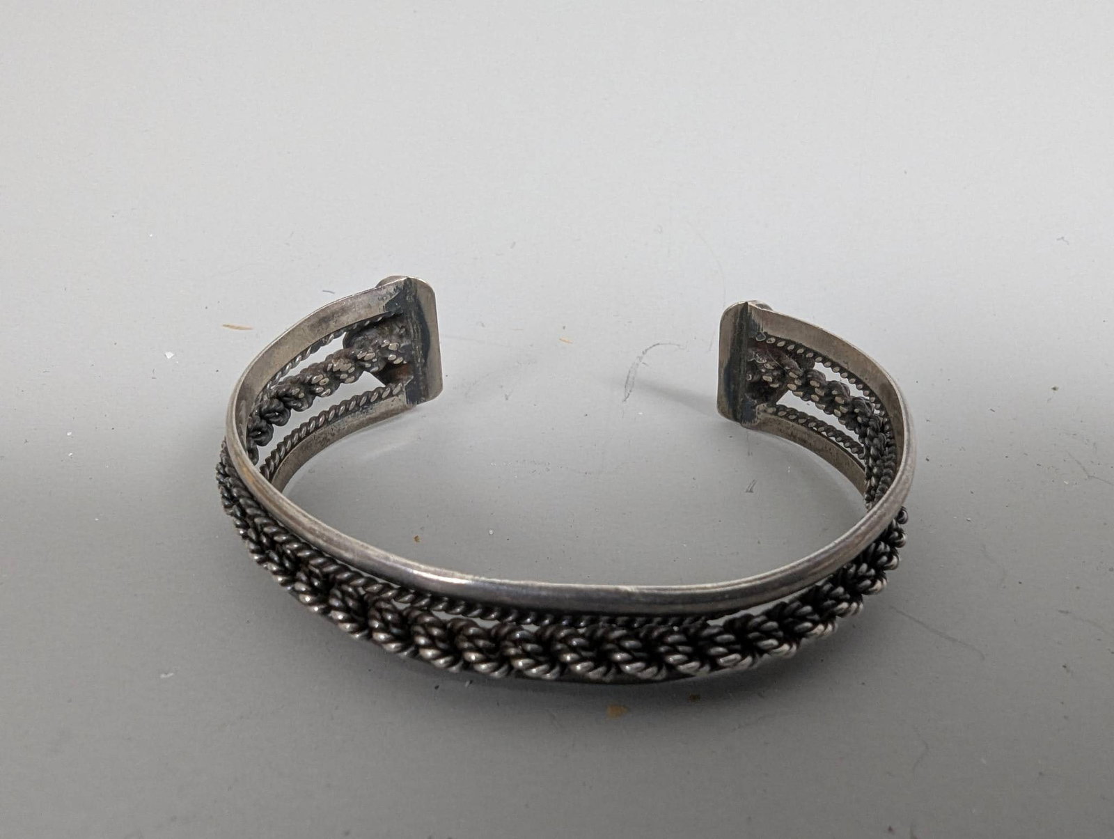 Mexico Sterling Silver Bracelet with Rope Braided Design Signed: Sterling silver cuff bracelet weighing 25 grams and created in Mexico. The bracelet features a rope-braided textured design with a vintage aesthetic. The craftsmanship includes intricate detailing alo