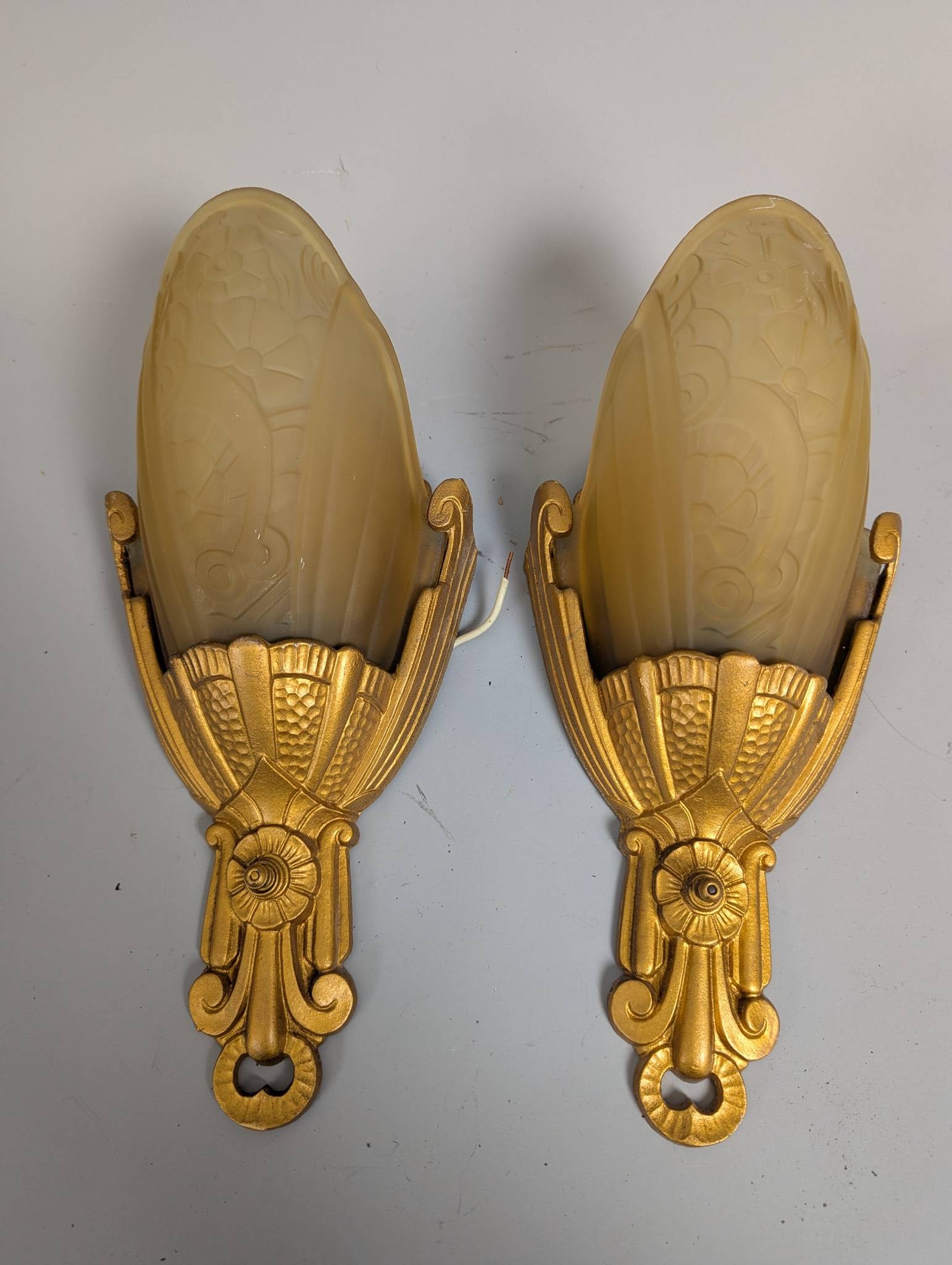 Art Deco Slip Shade Wall Sconces by Lincoln Circa 1920-30: Art Deco slip shade wall sconces manufactured by Lincoln, circa 1920-30. The model is from the Fleurette or The Nile Group Series 8400 line. Each sconce features light amber or peach satin glass shade